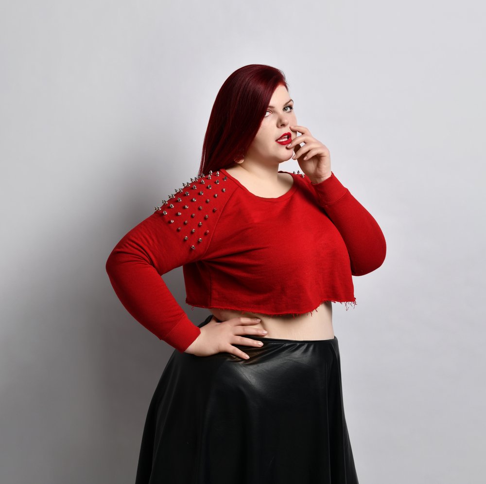 Chica de talla grande luciendo una blusa corta roja y una falda a la cintura. I Foto: Shutterstock.