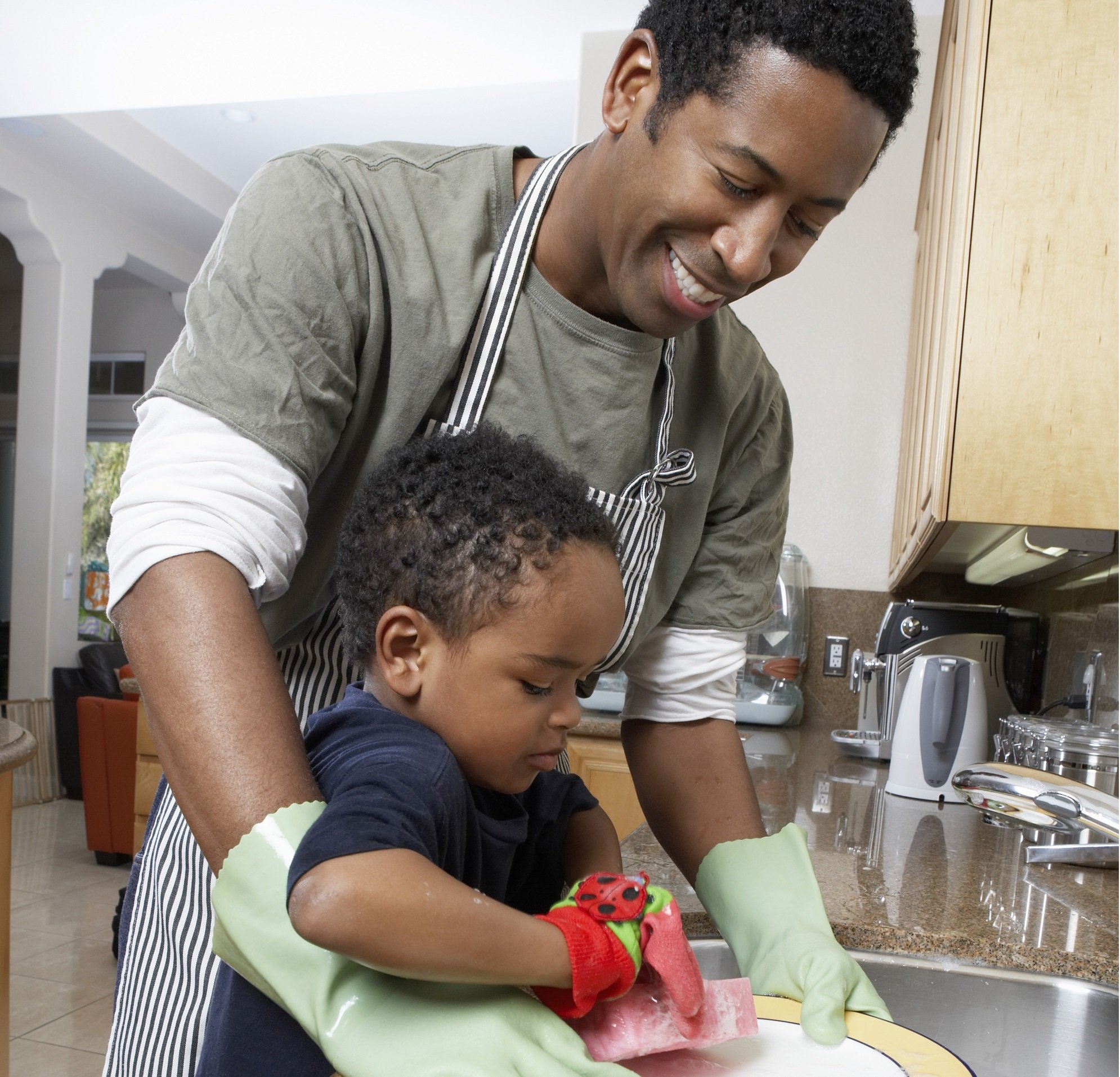 Padre e hijo pequeño lavan los platos juntos. | Foto: Shutterstock
