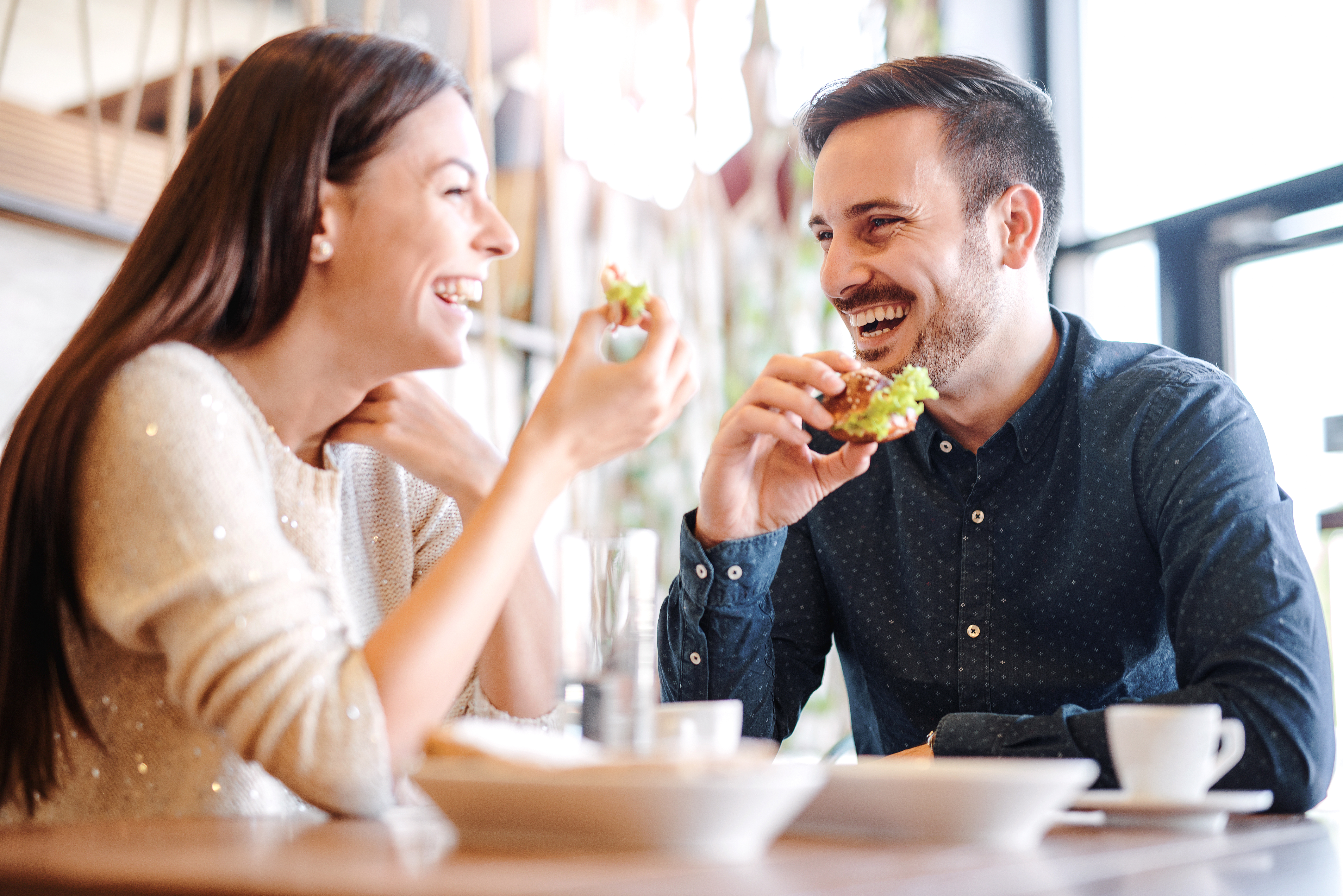 A couple laughing while enjoying a meal together | Source: Shutterstock