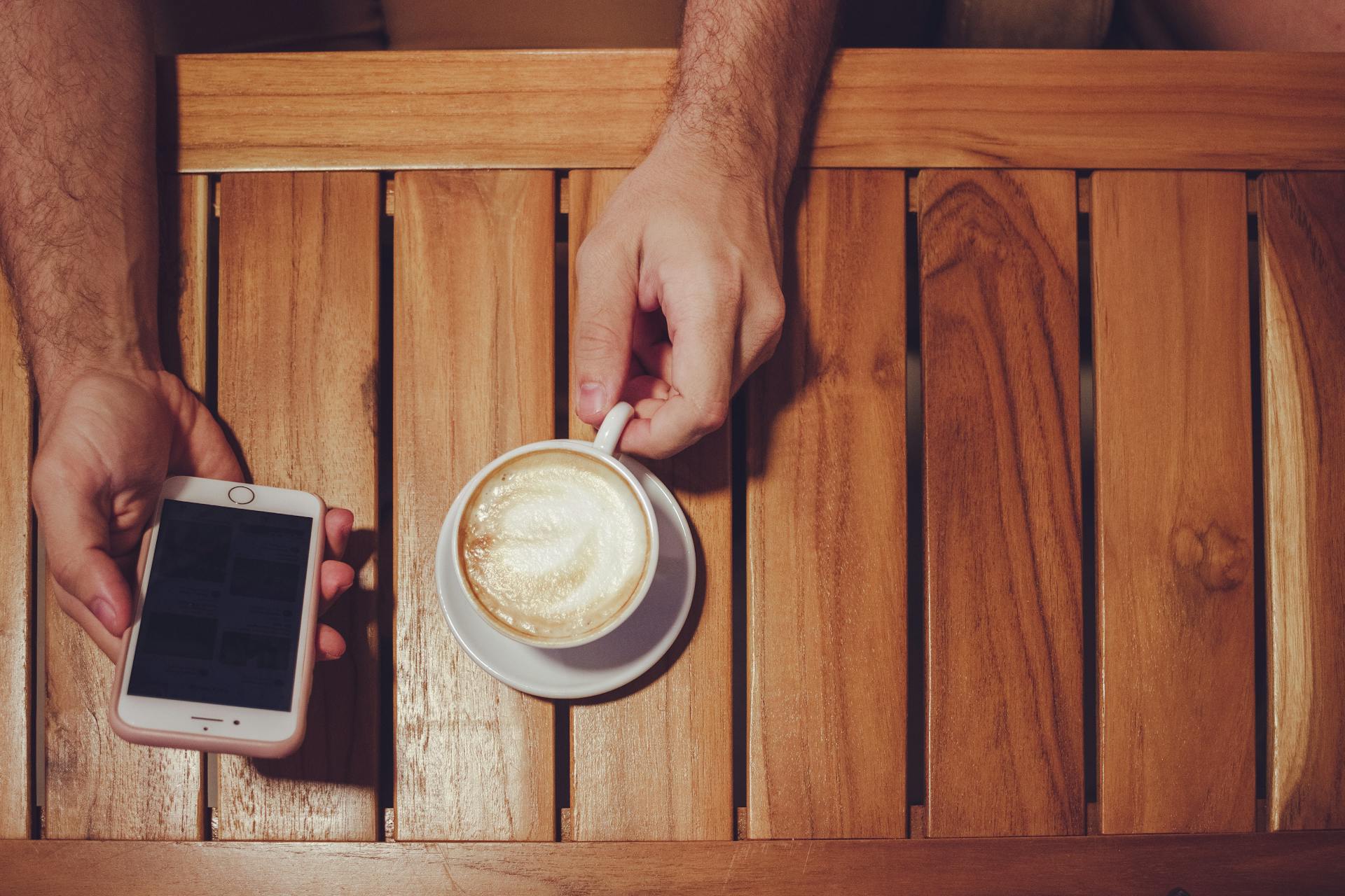 A man drinking coffee and using his phone | Source: Pexels