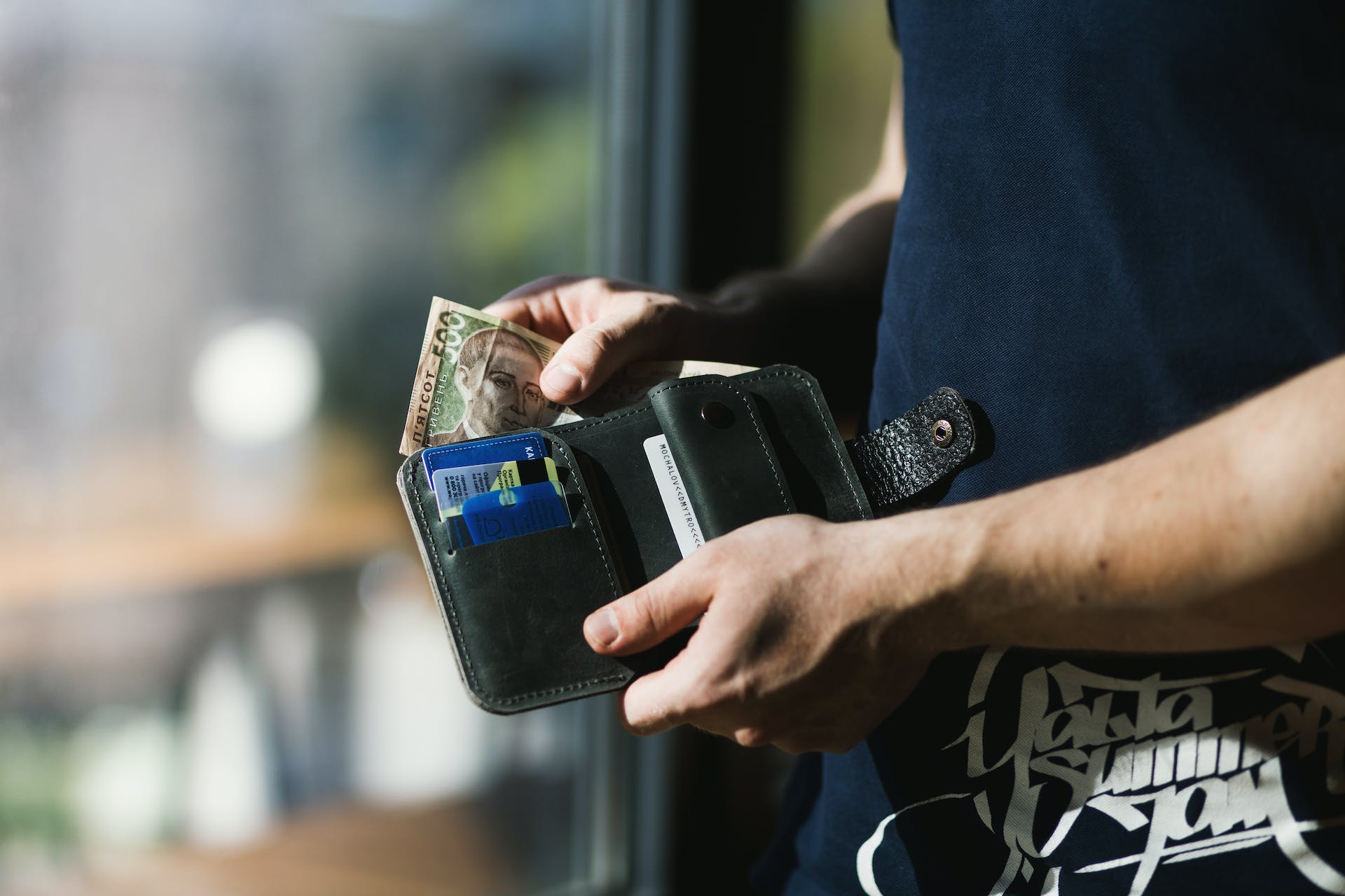 Person holding a black leather wallet with money | Source: Pexels