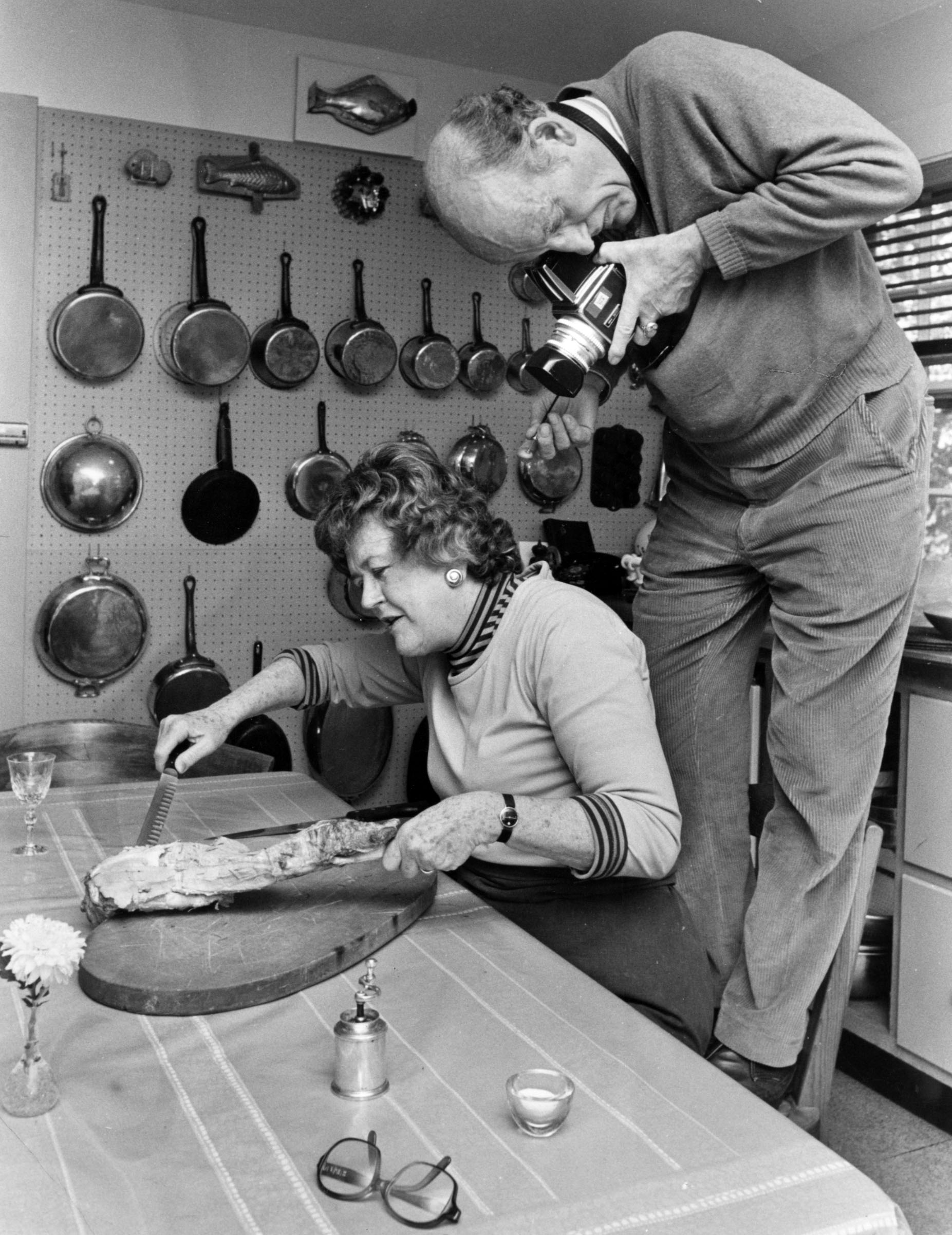 Julia Child slices a leg of lamb as her husband, Paul Child, photographs for a book illustration over her shoulder. Photo: Getty Images