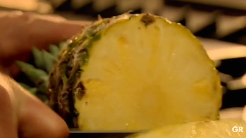 Gordon Ramsay slices into a ripe pineapple after demonstrating his simple freshness test. He advises gently pulling one of the leaves from the crown before cutting into the fruit, explaining that if it comes away easily, the pineapple is typically ripe and ready to enjoy. | Source: YouTube/ Gordon Ramsay