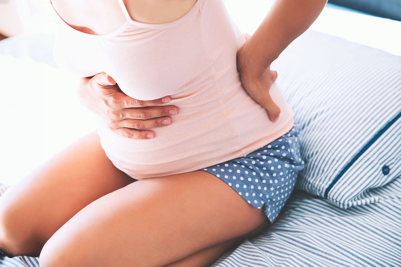 Pregnant woman holds her stomach in bed. | Source: Shutterstock