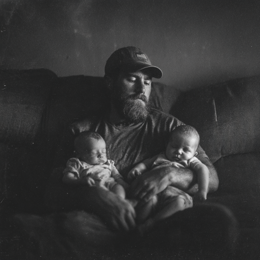 A man on a couch holding two babies | Source: Midjourney