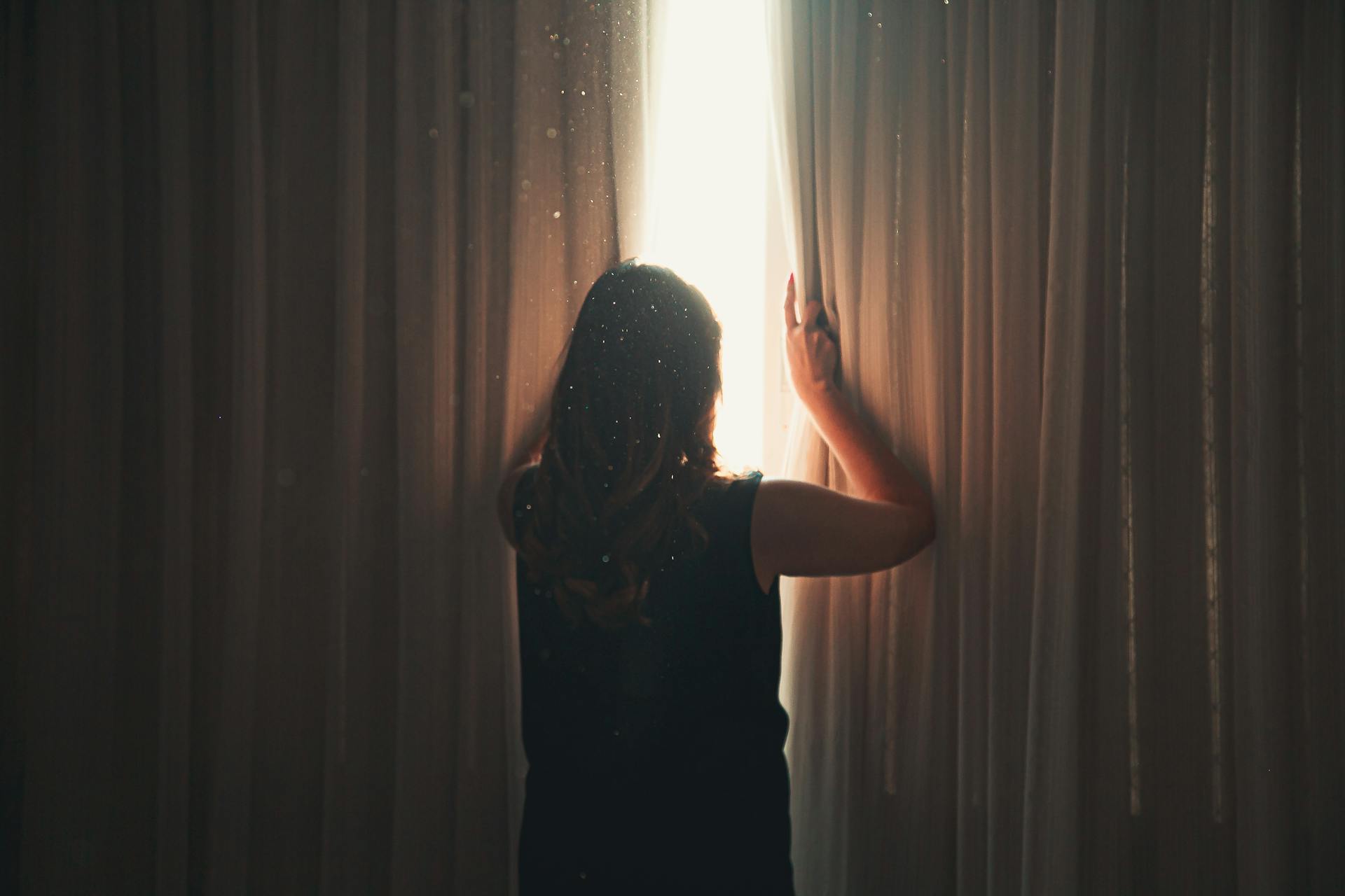 A woman looking outside a window | Source: Pexels