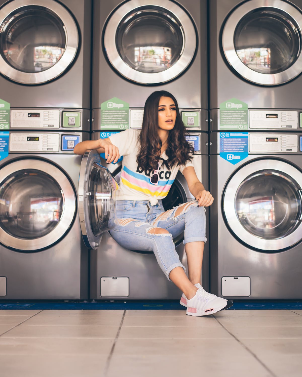 Joven recostada de una lavadora en una lavandería. | Foto: Pexels