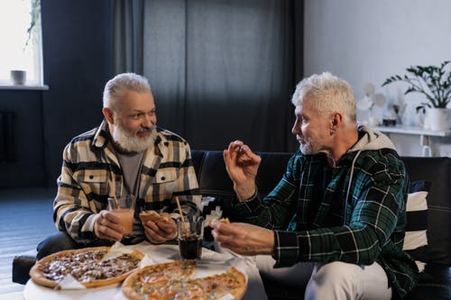 Two elderly men talking to each other over a meal | Photo: Pexels