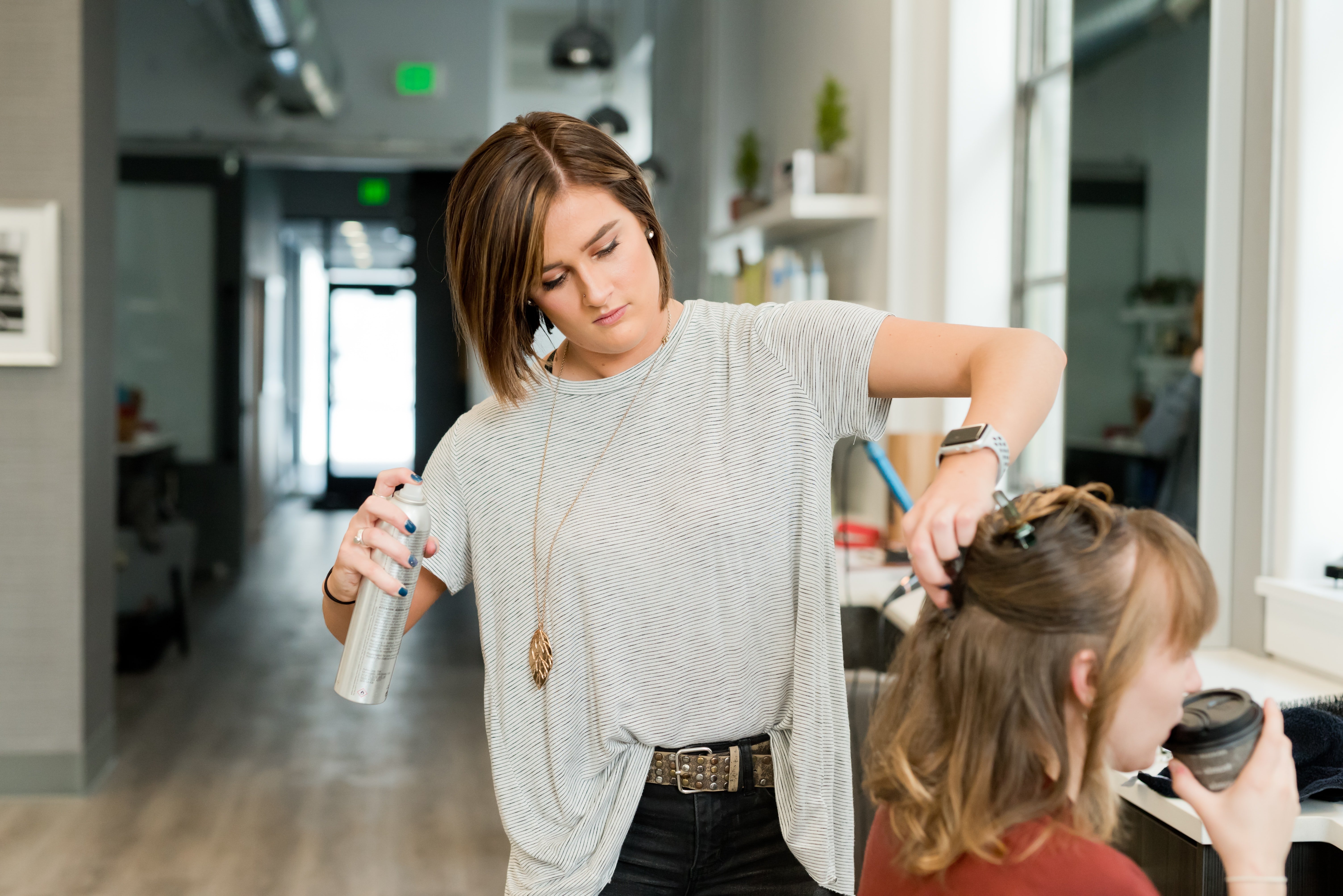 Hair stylist spraying hair spray on client | Unsplash