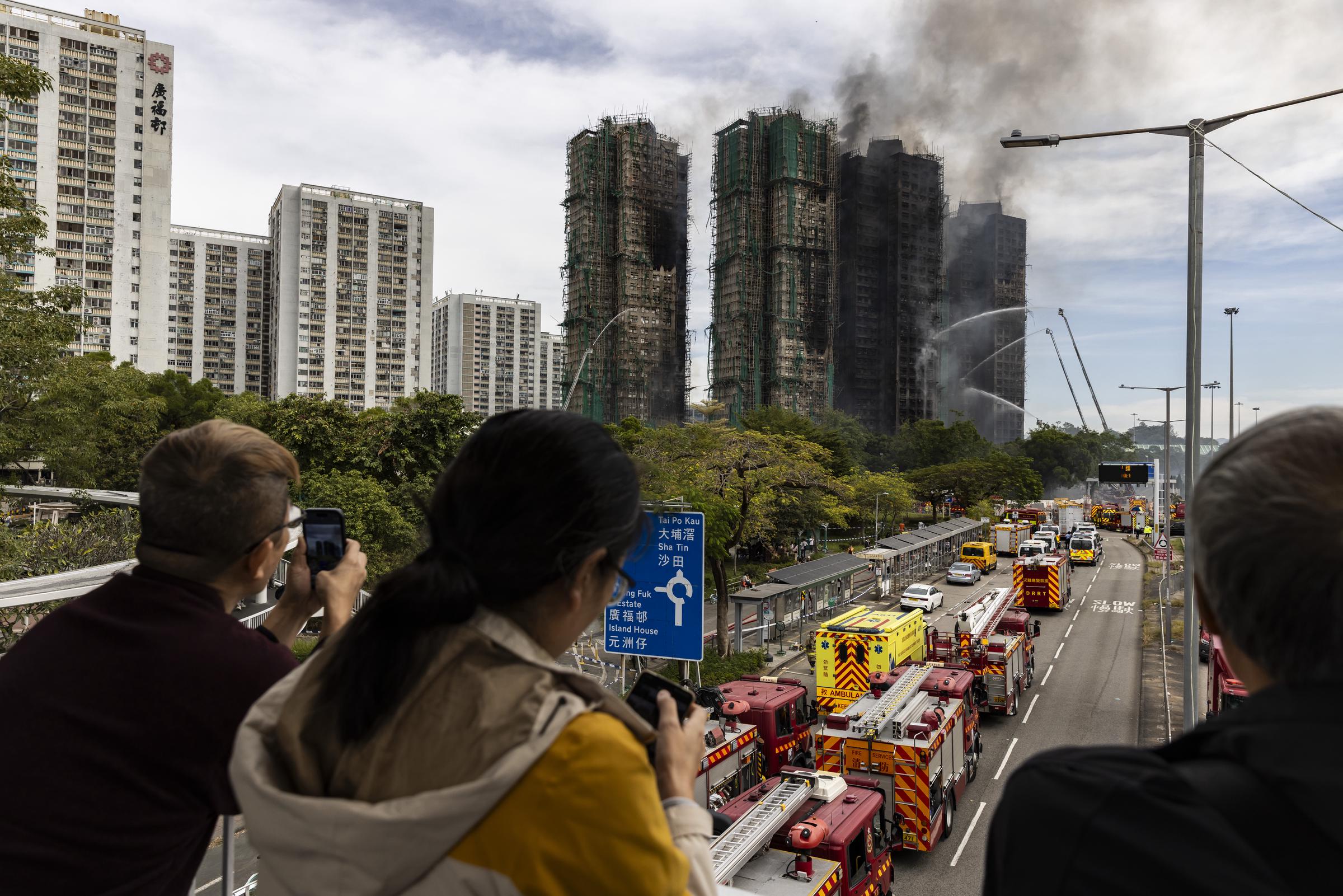 People watch residential buildings that continue to burn at Wang Fuk Court in the Tai Po district on November 27, 2025, in Hong Kong, China. | Source: Getty Images