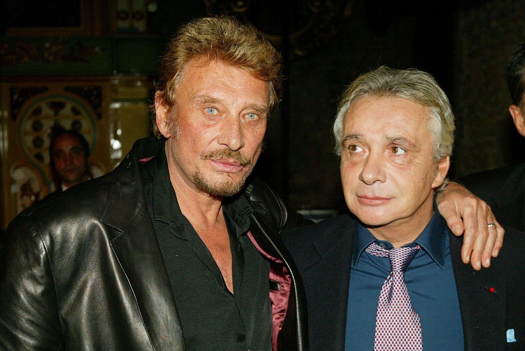 Johnny Hallyday (L) et Michel Sardou assistent à la cérémonie où le producteur et directeur artistique français, Jean-Claude Camus, a reçu la croix "Arts et lettres". | Photo : Getty Images Johnny Hallyday (L) et Michel Sardou assistent à la cérémonie où le producteur et directeur artistique français, Jean-Claude Camus, a reçu la croix "Arts et lettres". | Photo : Getty Images