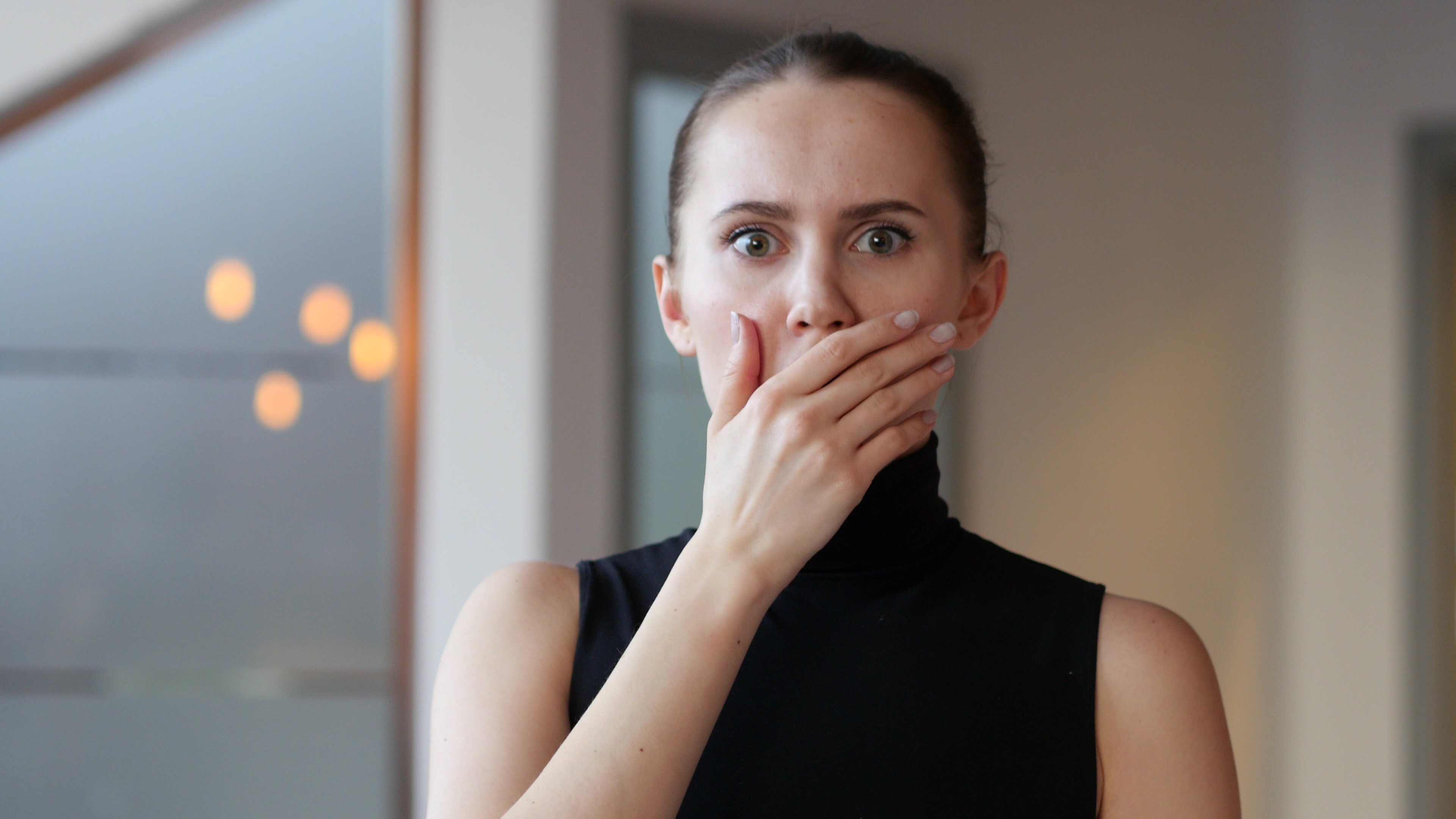 A woman standing with her hand on her mouth | Source: Shutterstock