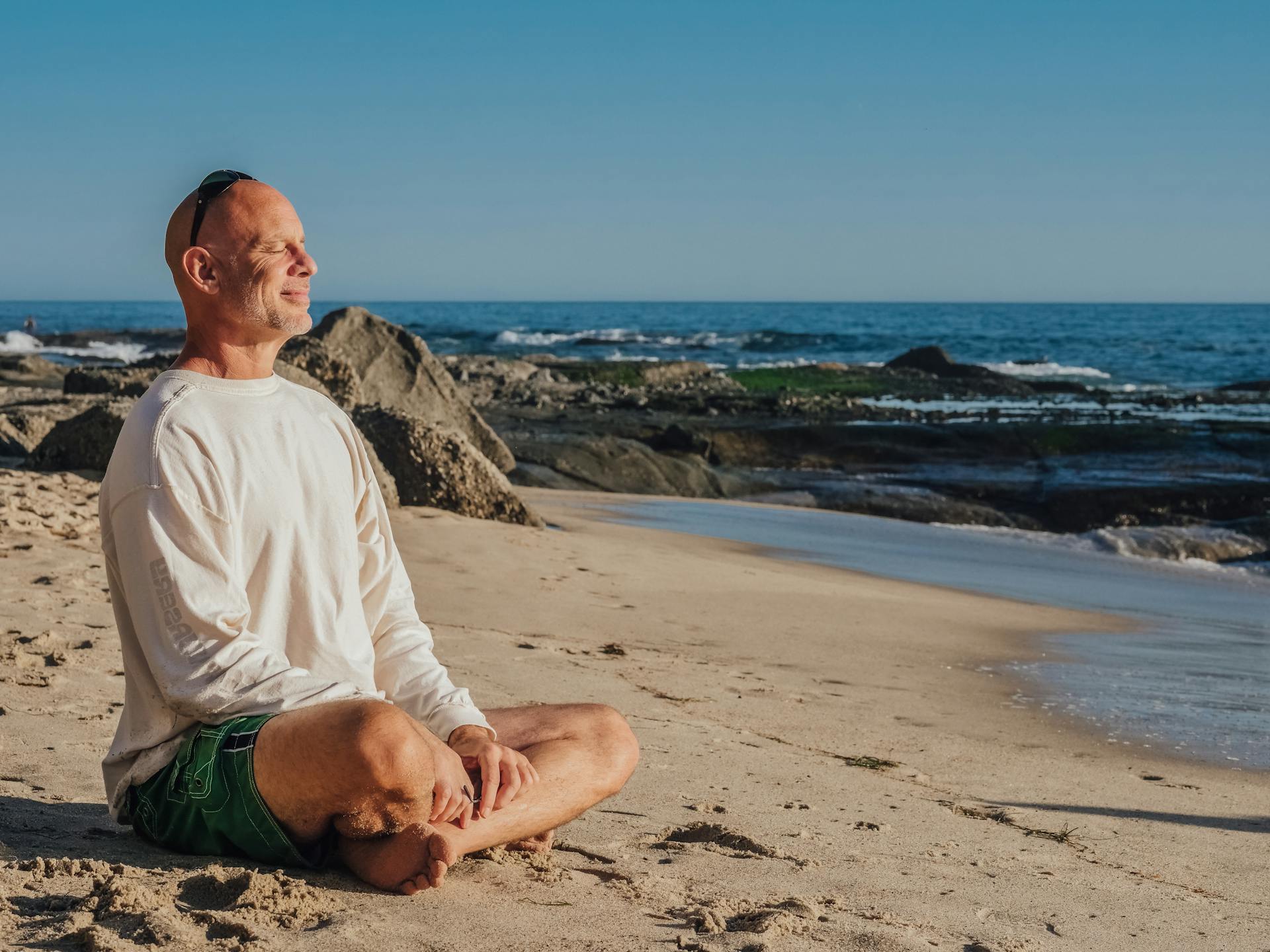 A man smiles while doing yoga on the beach | Source: Pexels