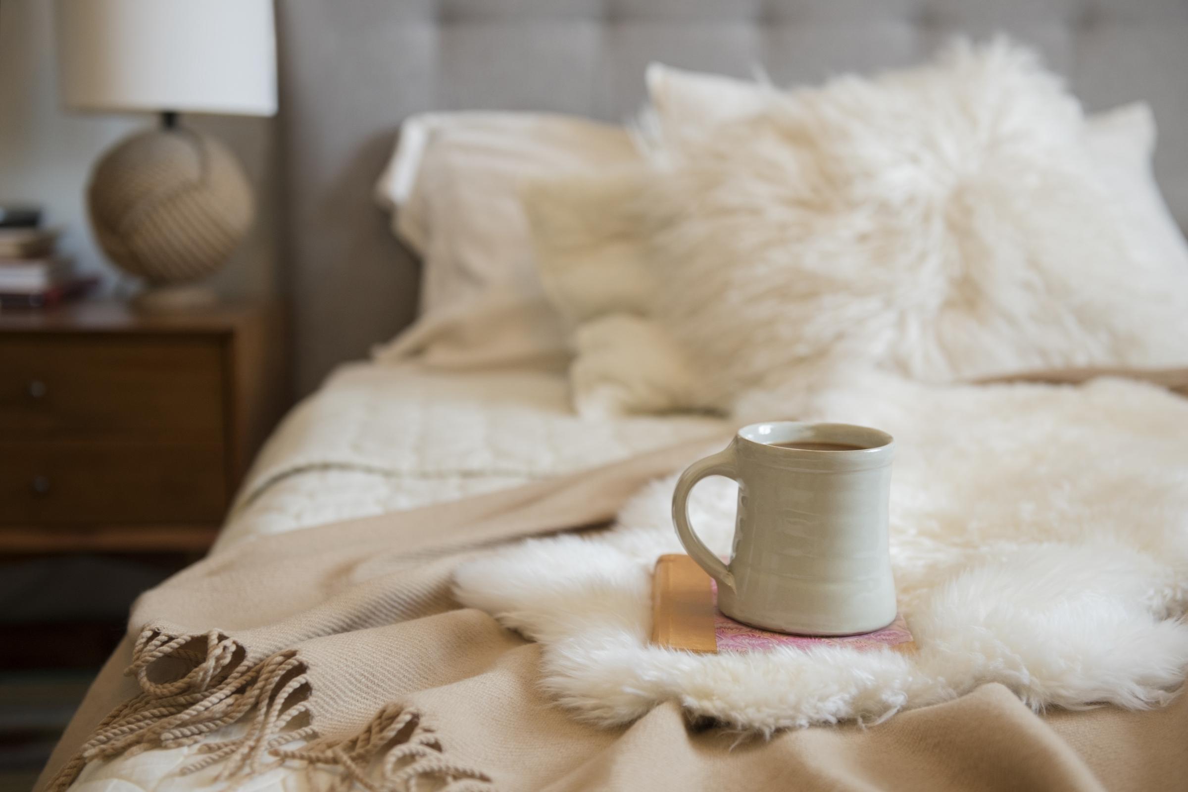 A cup of coffee placed ontop of a book on a bed | Source: Getty Images
