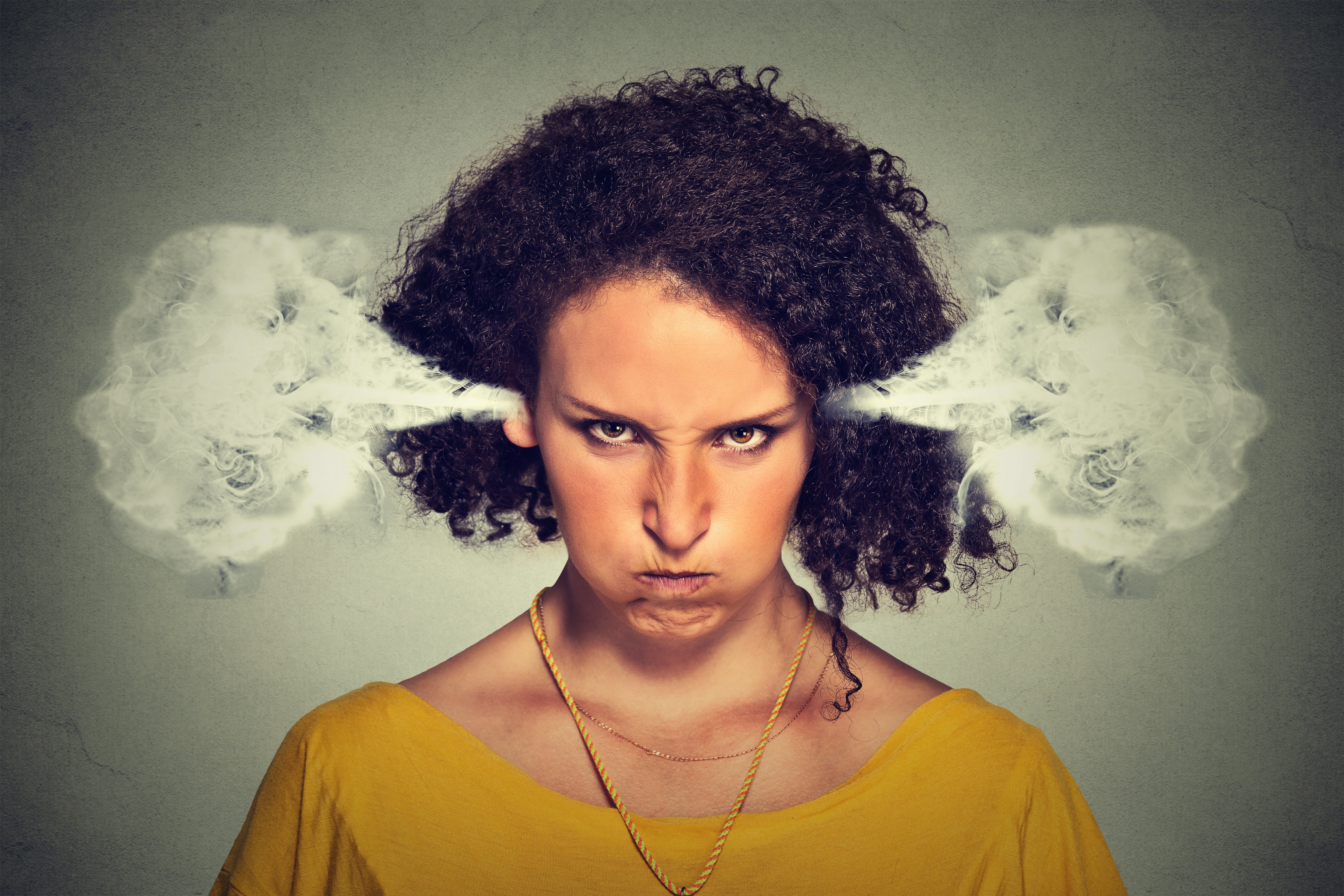 Woman in mustard top fuming with anger. | Source: Shutterstock