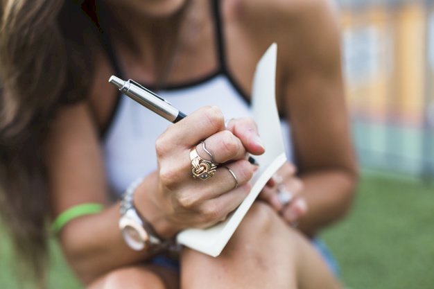 Une femme exhibant ses bagues tout en écrivant dans un carnet de notes. | Freepik Une femme exhibant ses bagues tout en écrivant dans un carnet de notes. | Freepik