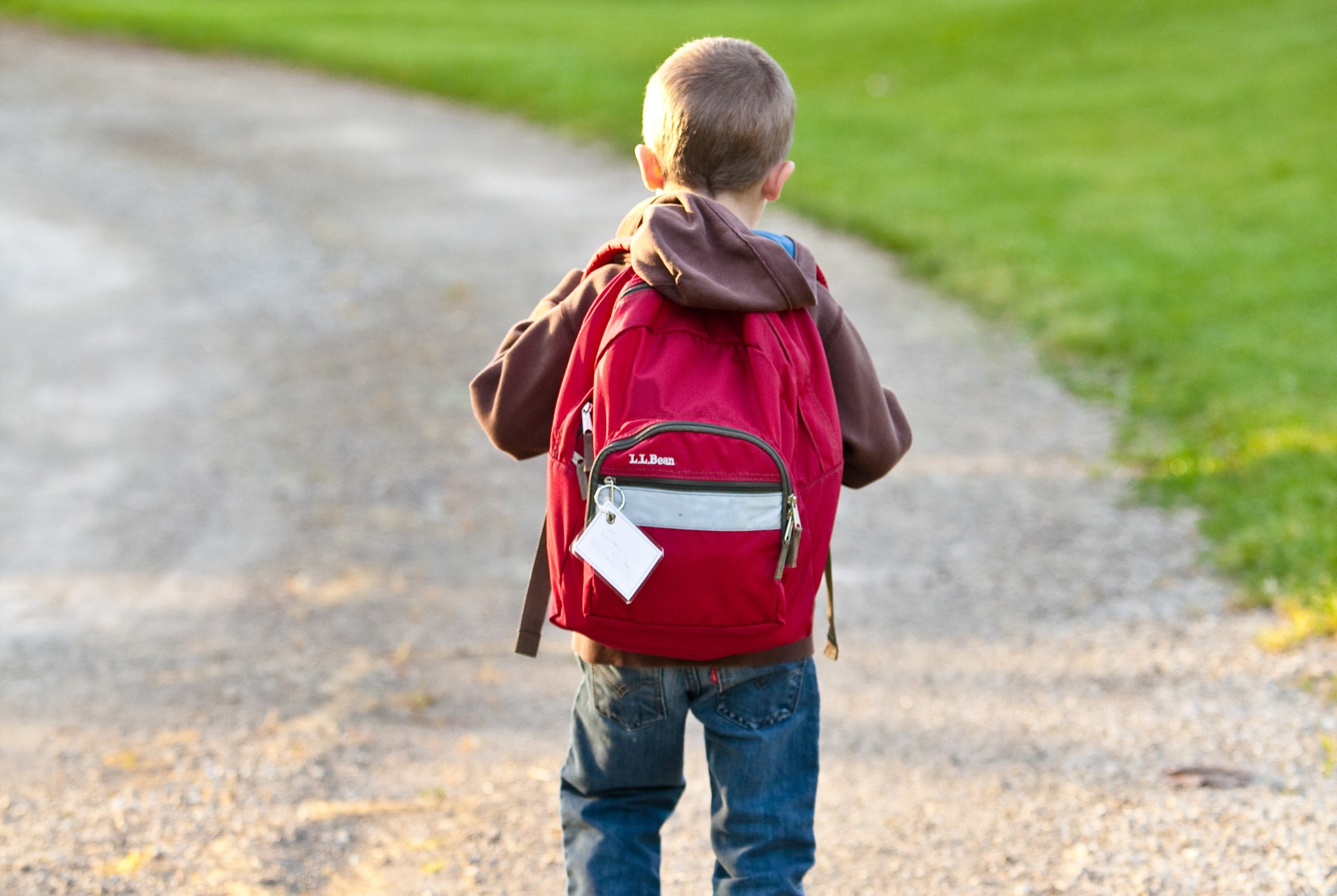 A little boy carrying a backpack as he walks down a street | Source: Pexels