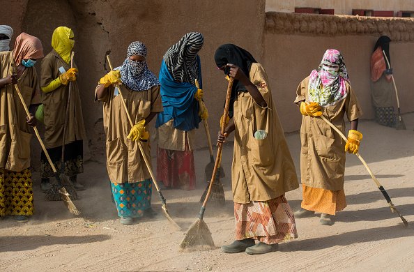 Nigerische Frauen und Männer fegen die Straße, Agadez, 2018 | Quelle: Getty Images