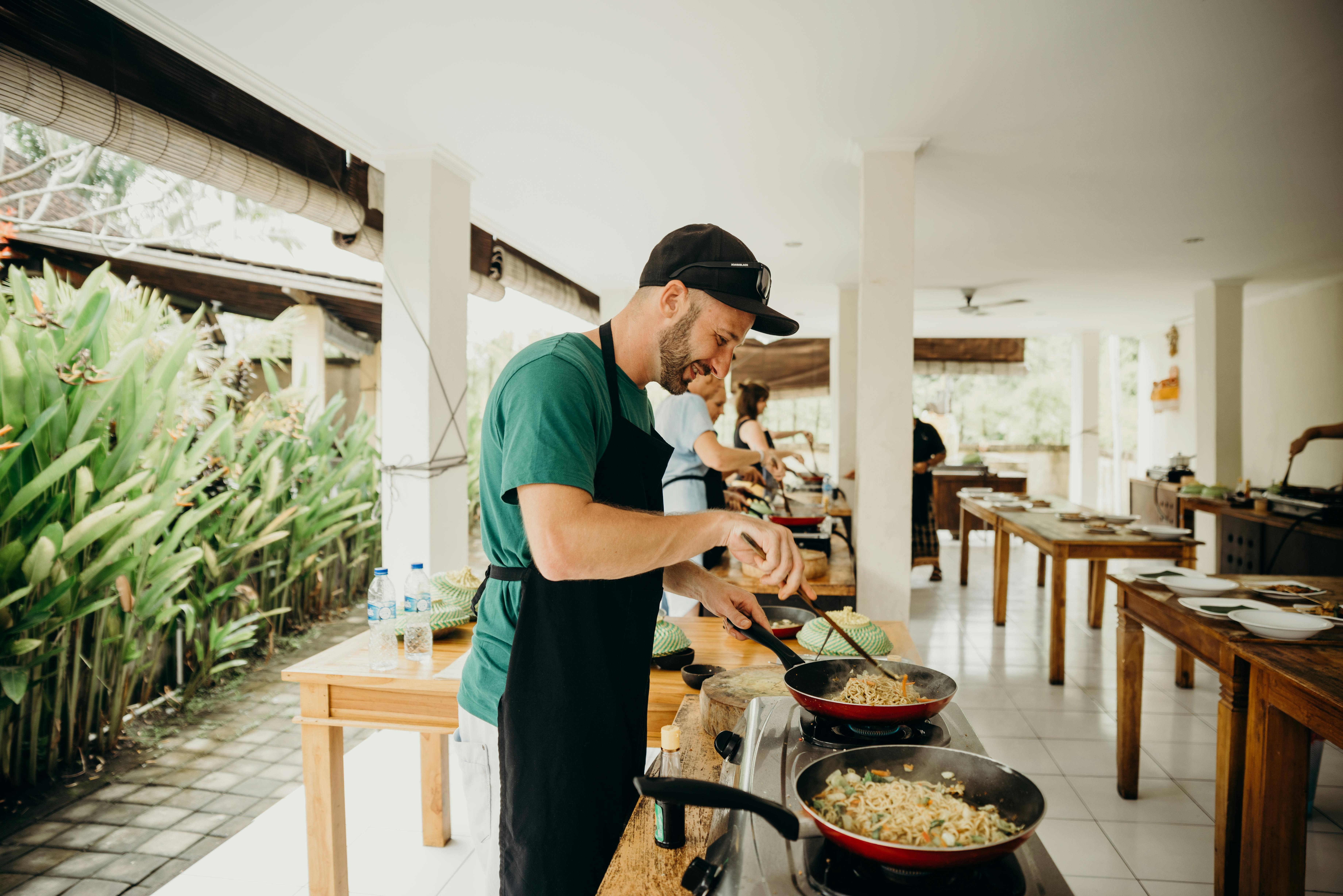 A Man Wearing Black Apron Cooking Food in a Cooking Competition | Source: Pexels