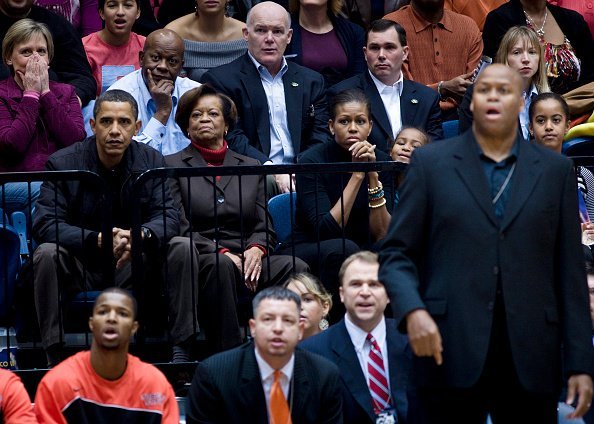 Barack Obama watches along with his mother in law Marian Robinson (2L) wife first lady Michelle Obama (3L) daughter Sasha Obama (3R), brother in law Craig Robinson (2R) and daughter Malia Obama (R) during a college basketball game at George Washington University November 28, 2009, in Washington, DC. | Source: Getty Images.