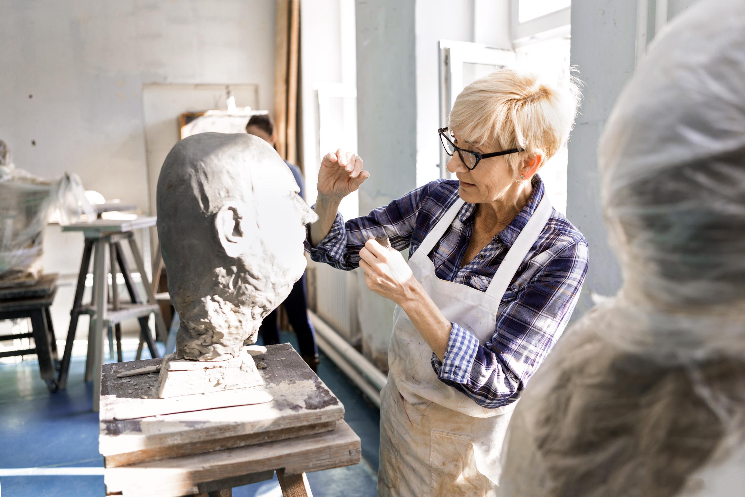 Senior woman sculpting a head in an art studio | Source: Getty Images