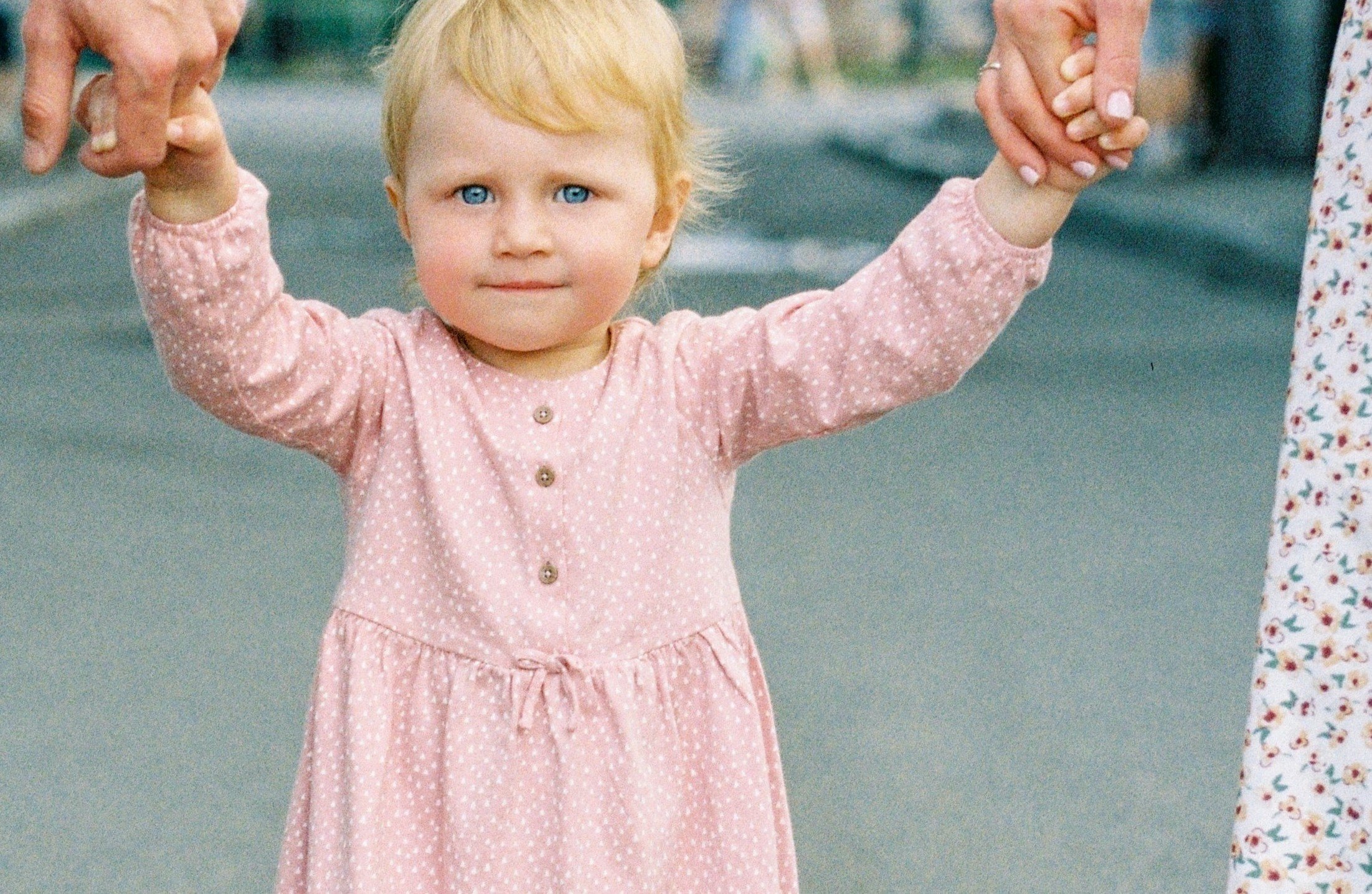 Una niña pequeña tomada de las manos con sus padres. | Foto: Pexels