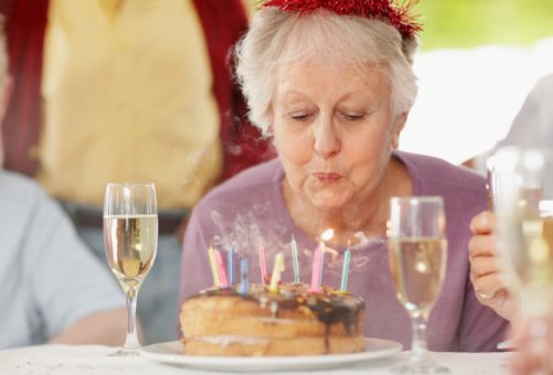 An elderly woman pictured blowing out the candles on a birthday cake | Photo: Getty Images
