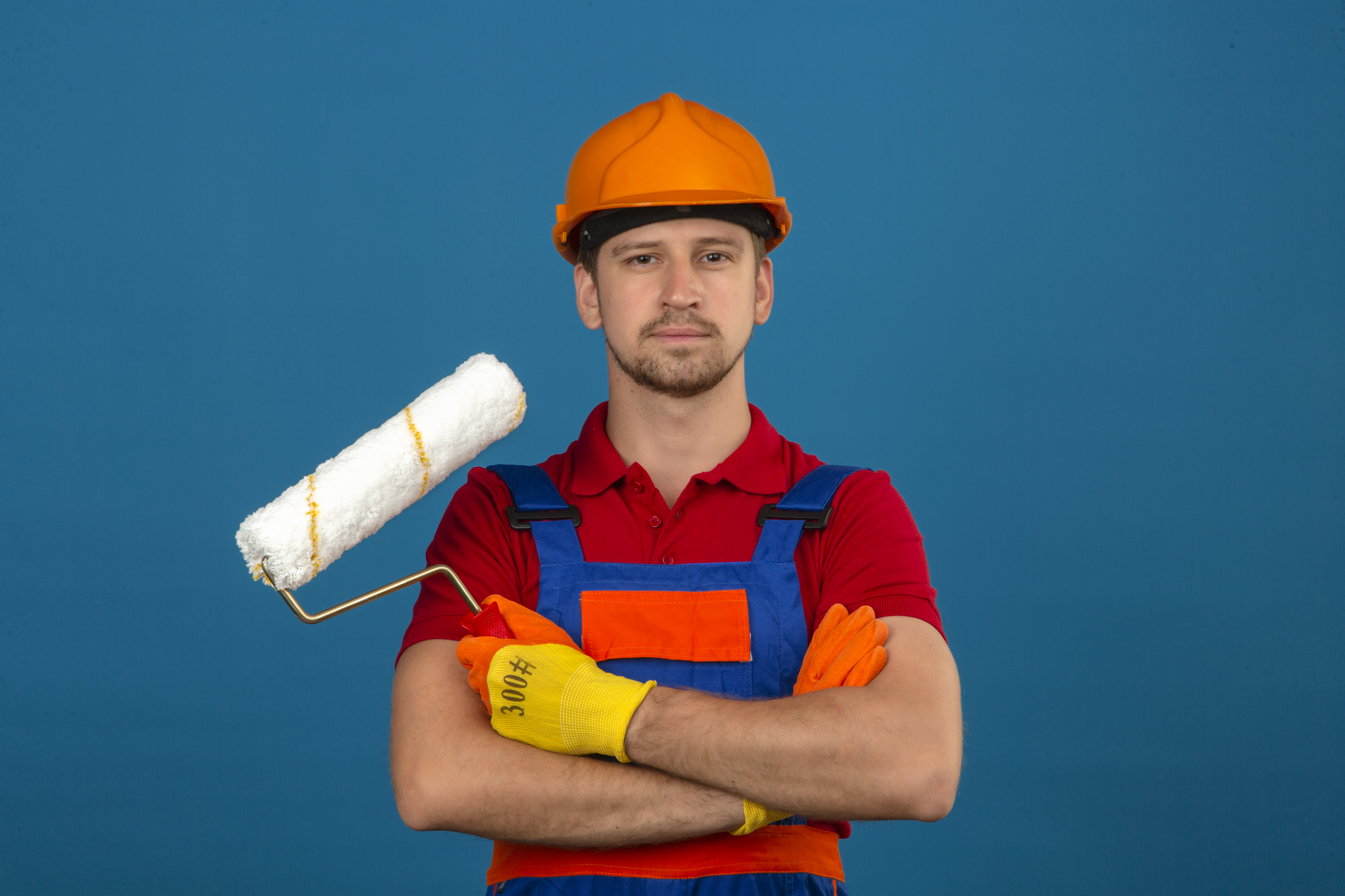 A man in construction uniform with crossed arms while holding a roller | Source: Freepik