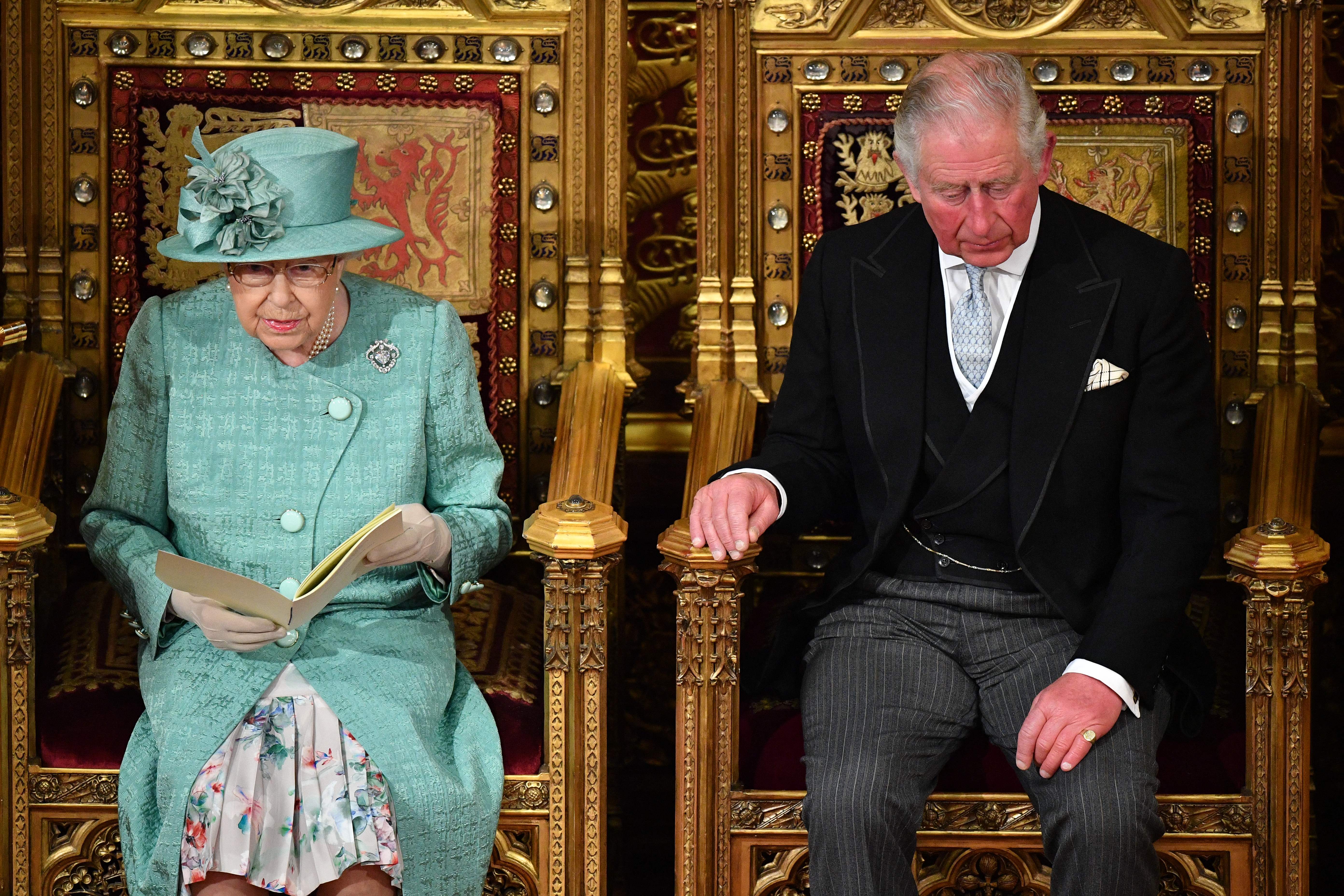 During the State Opening of Parliament on 19 December 2019, Queen Elizabeth II is seen seated on the Sovereign's Throne in the House of Lords chamber as she delivers the Queen's Speech, with Prince Charles, Prince of Wales, positioned beside her in a formal display of constitutional duty, the ornate setting underscoring the centuries-old traditions of the British monarchy.