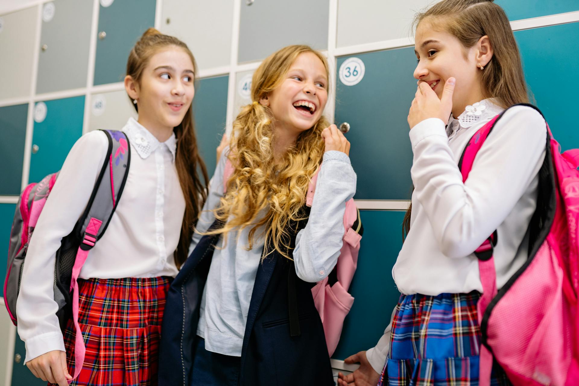 Three schoolgirls sharing a laugh in front of their lockers | Source: Pexels