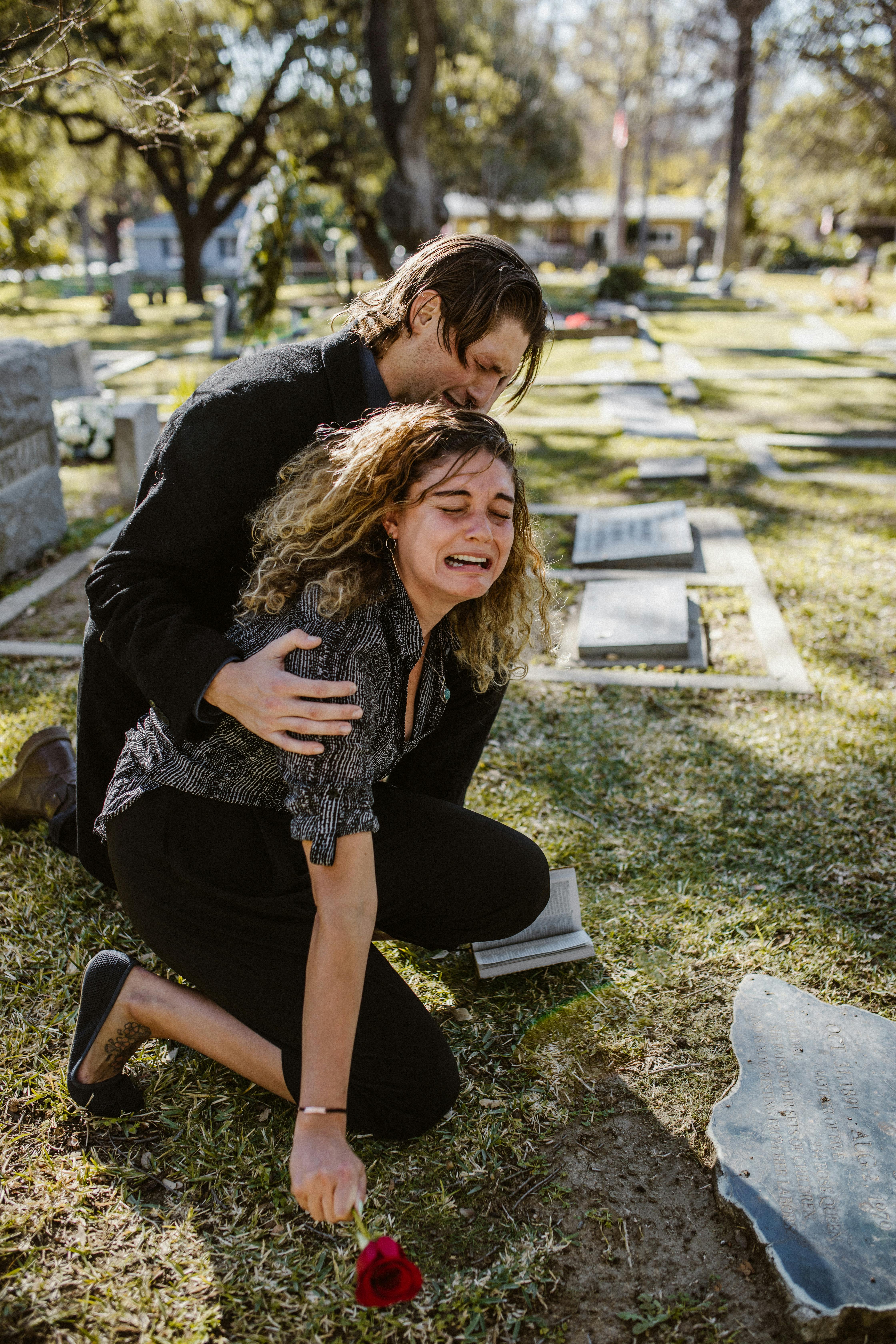 A young woman comforted by a man while crying at a gravesite | Source: Pexels
