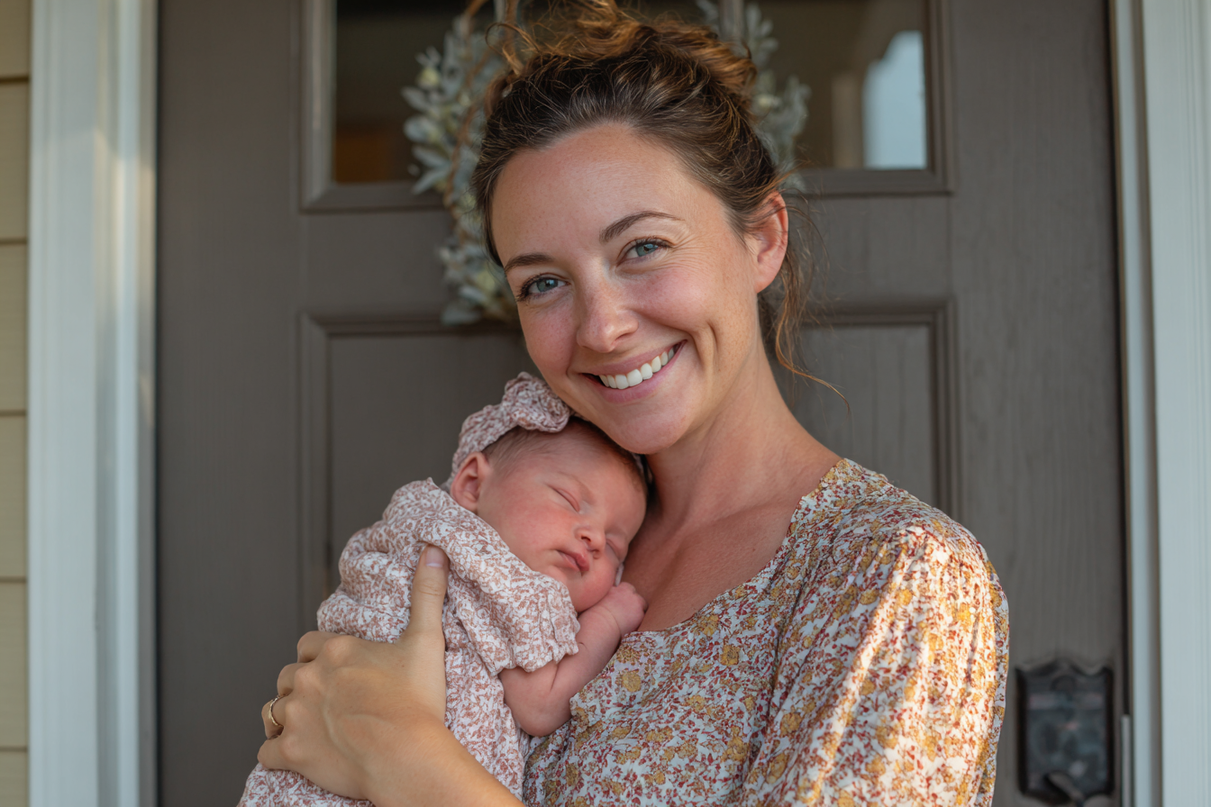A smiling woman holding her newborn baby girl | Source: Midjourney