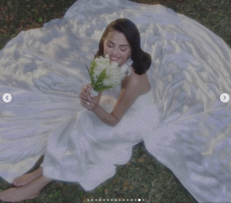 Selena Gomez sits barefoot on the grass in her wedding gown, holding a Lily of the Valley bouquet, as posted on September 27, 2025 | Source: Instagram/selenagomez