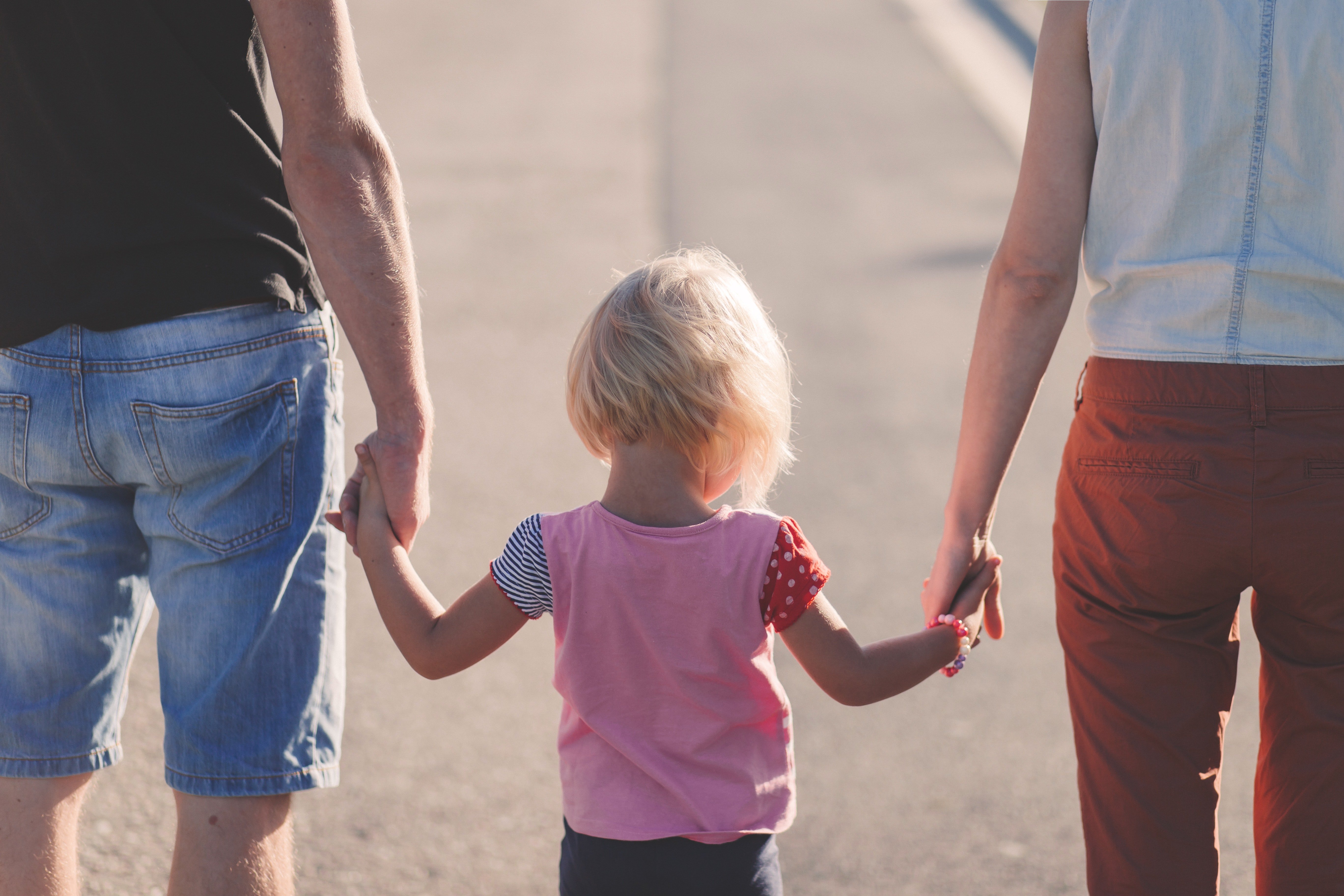Una pareja camina con su pequeña hija de la mano entre los dos. | Foto: Pexels