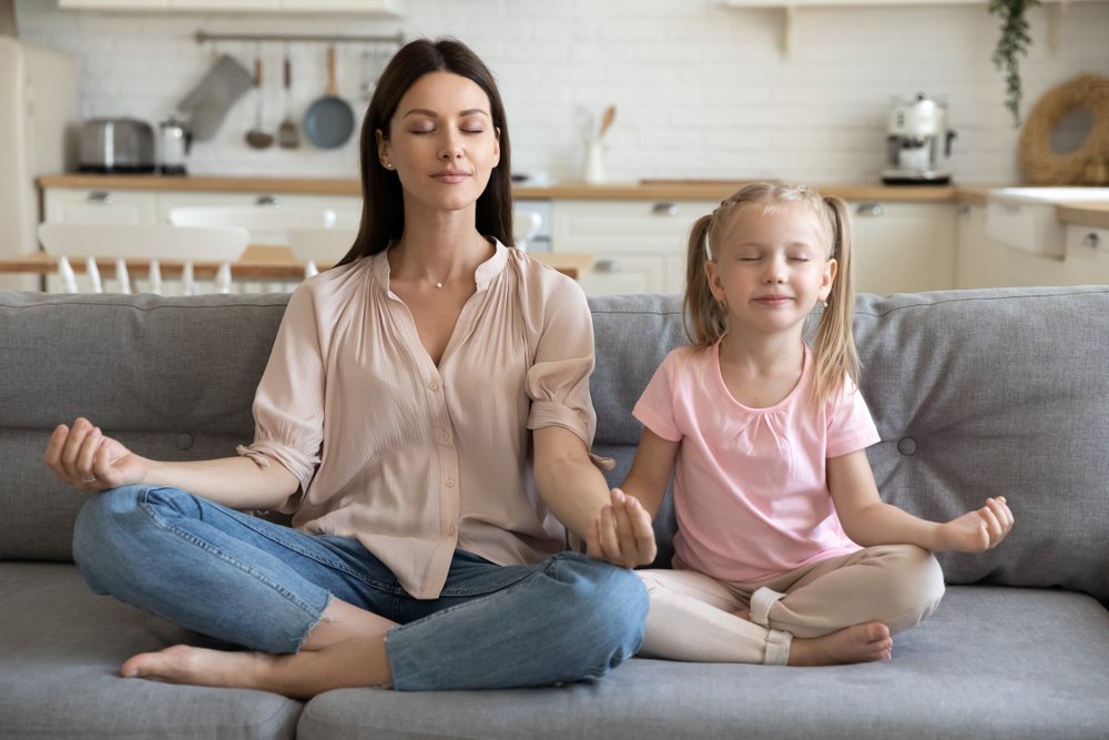 Madre e hija haciendo un ejercicio de meditación en el sofá. | Foto: Shutterstock Madre e hija haciendo un ejercicio de meditación en el sofá. | Foto: Shutterstock