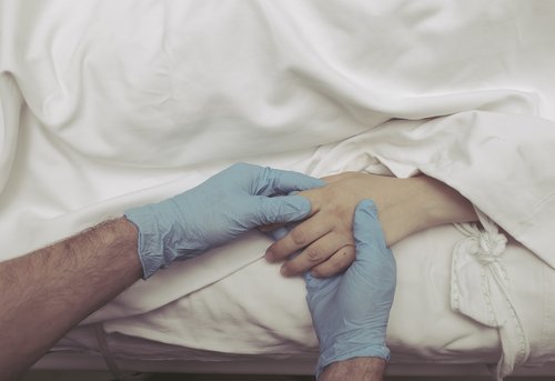 Persona tomando la mano de un paciente en el hospital. | Foto: Shutterstock