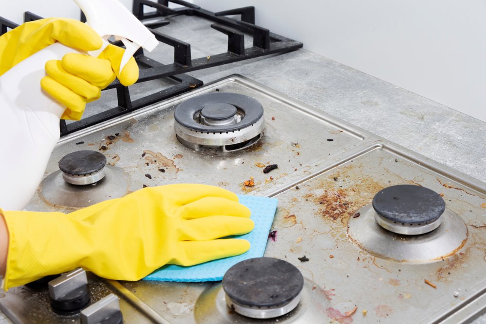 Manos con guantes limpiando la estufa. | Foto: Shutterstock