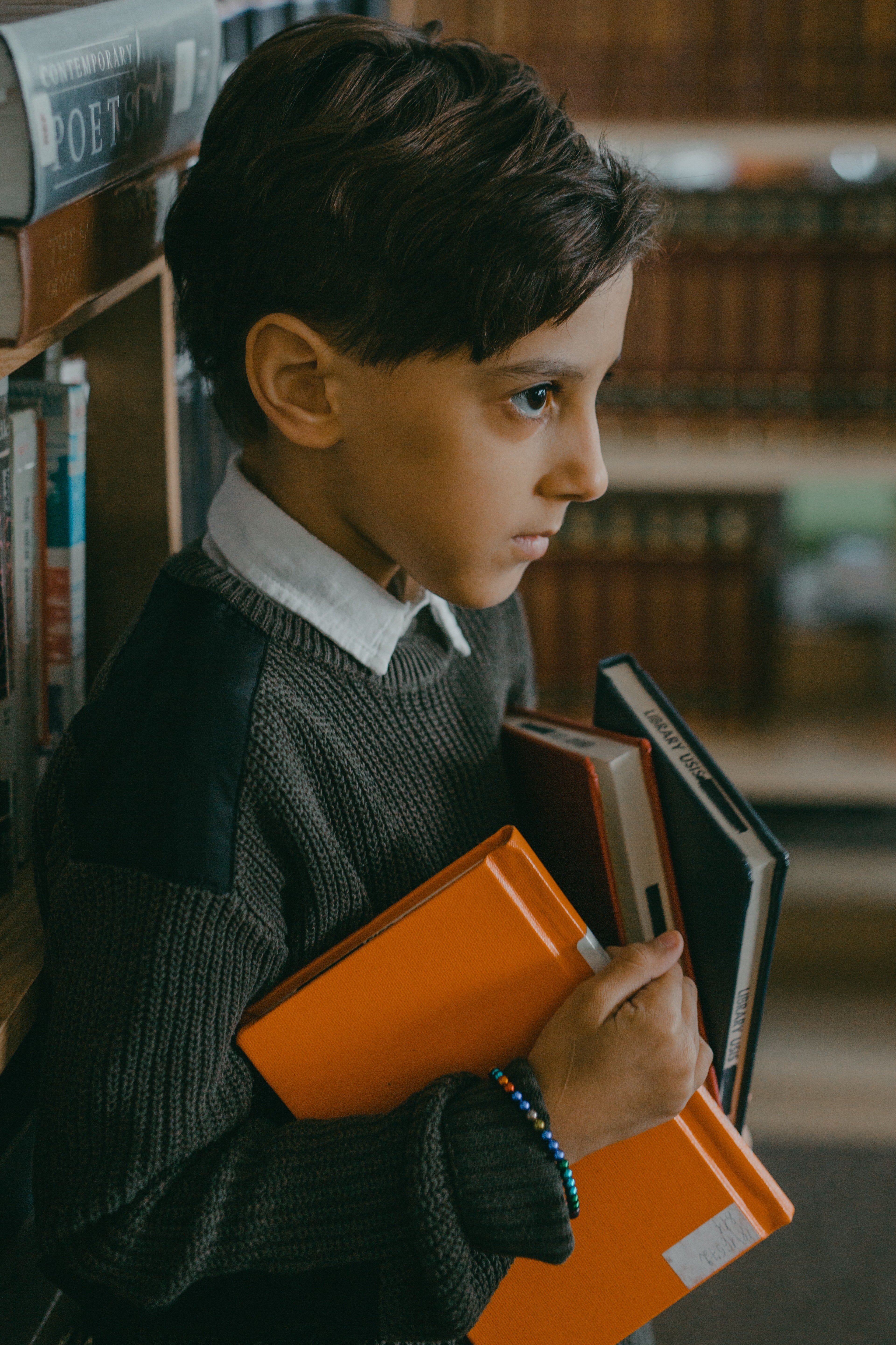 Un niño con rostro serio y varios libros en sus manos. | Foto: Pexels