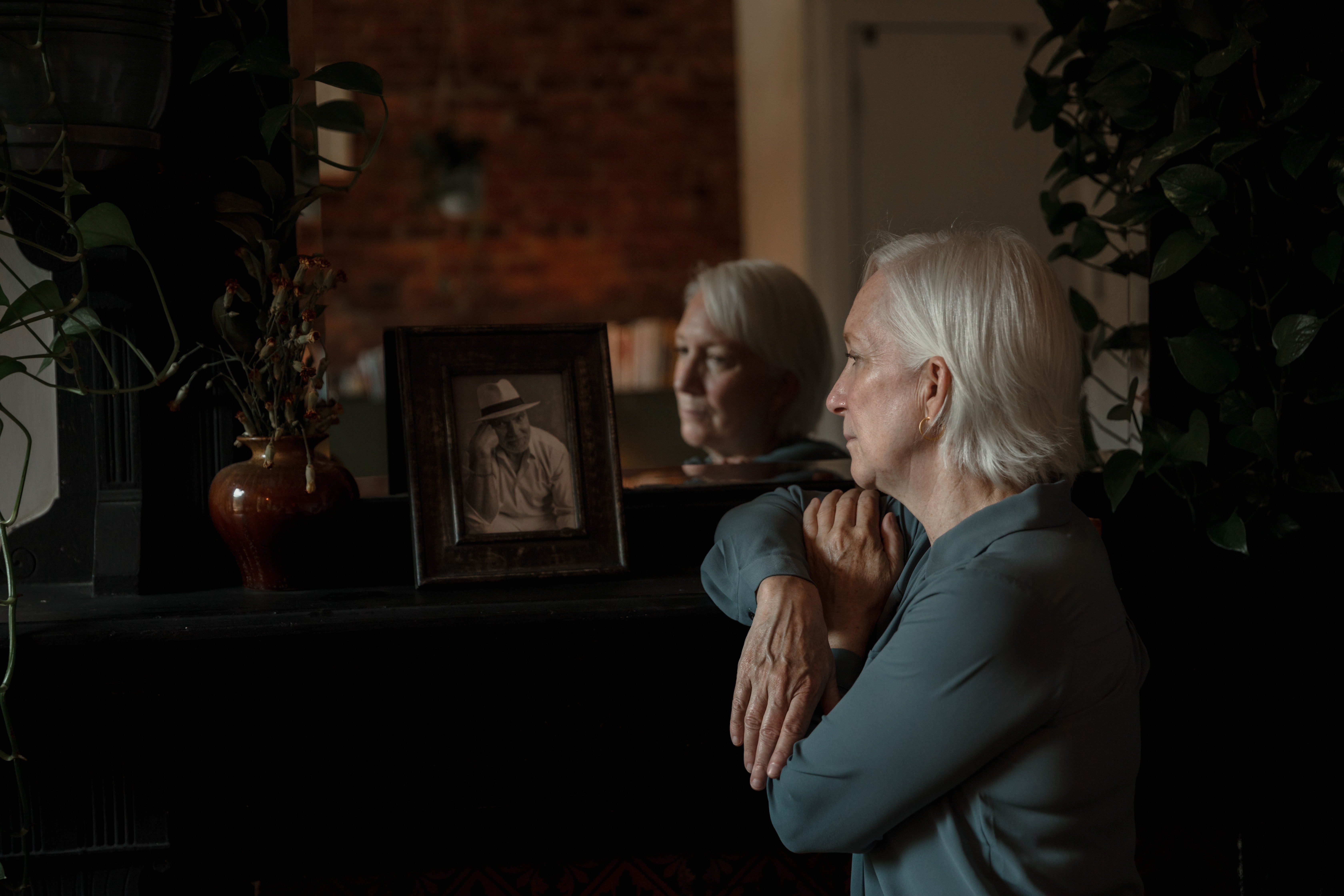 Anciana observando la fotografía de su difunto esposo. | Foto: Pexels