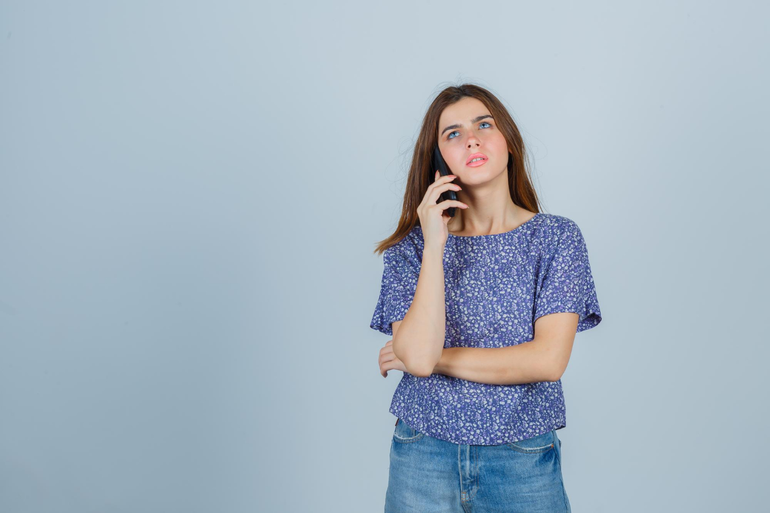 A young, distressed woman talking on the phone | Source: Freepik