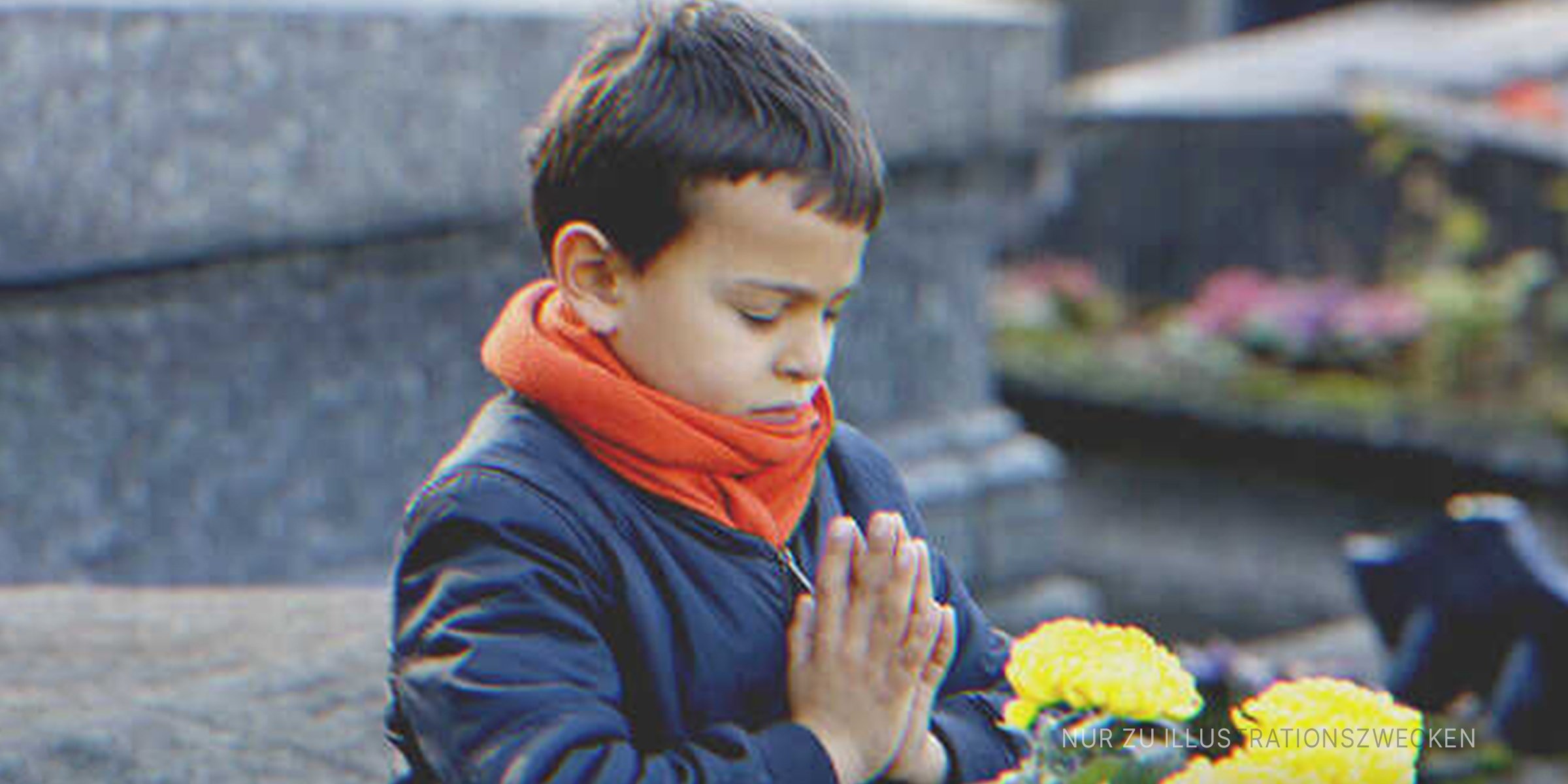 Kleiner Junge betet vor dem Grab seiner Mutter. | Quelle: Getty Images