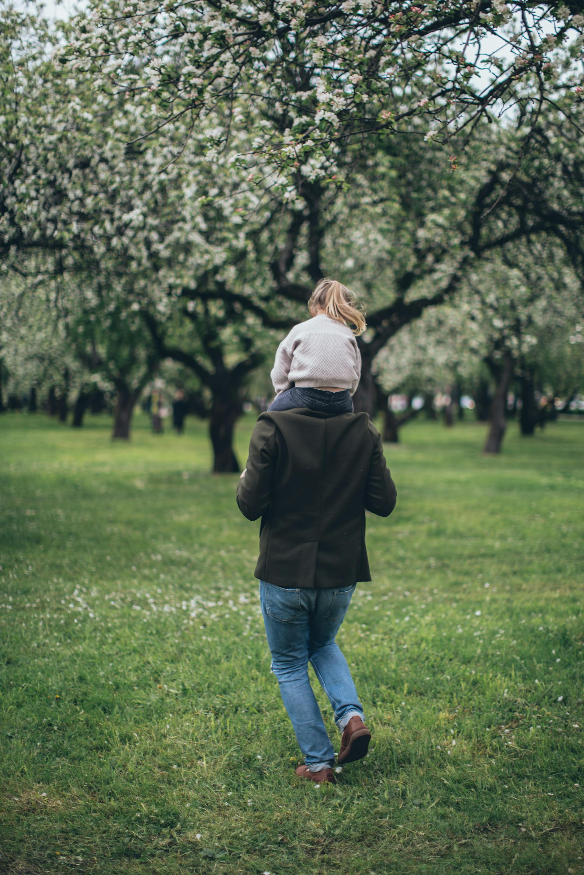 A man carrying his little daughter on his shoulders | Source: Pexels