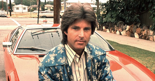 Ricky Nelson poses in front of a red car in 1974. | Source: Getty Images