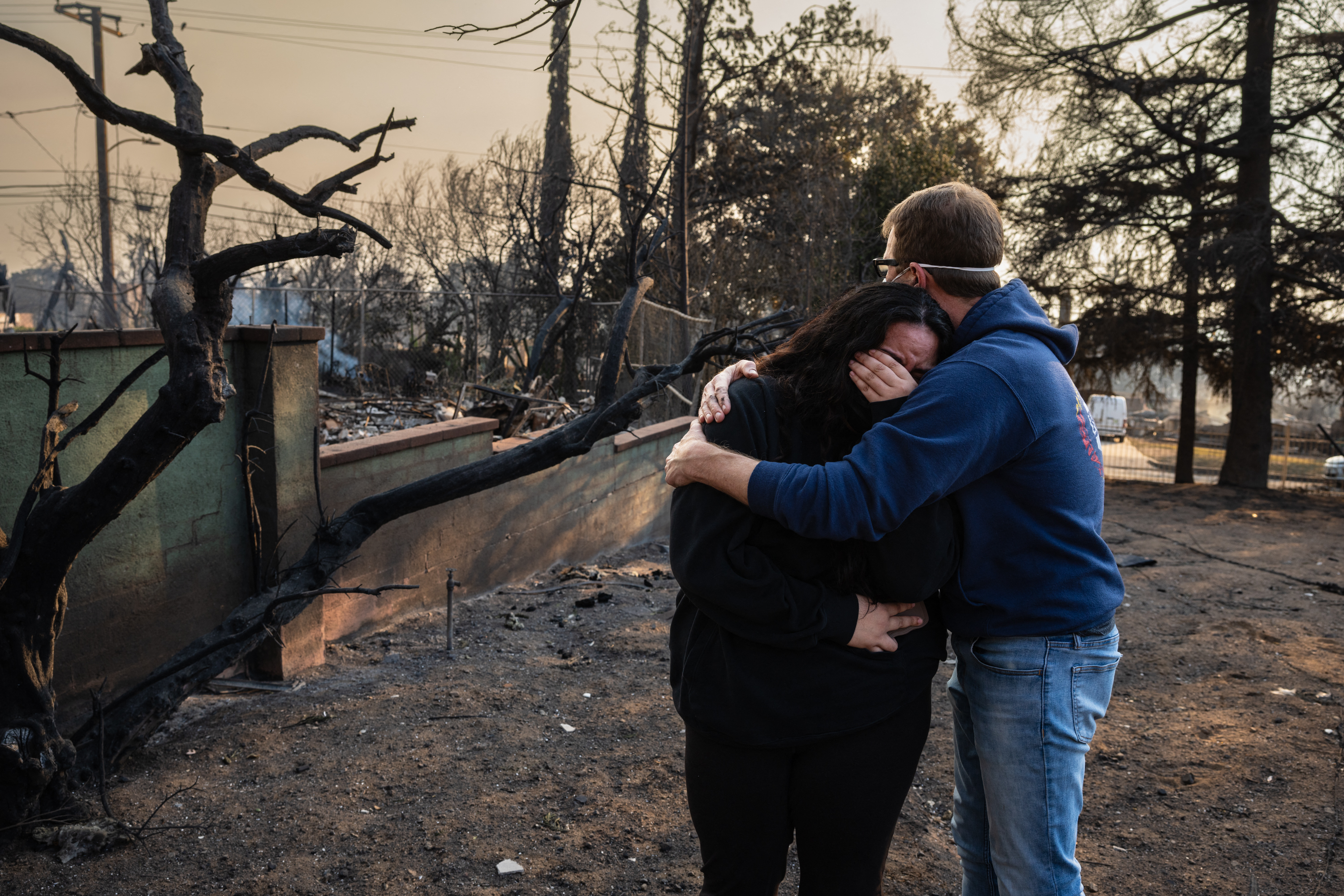 A man embracing his daughter on the charred ruins of their family home burned in the Eaton Fire on January 9, 2025, in Altadena, California. | Source: Getty Images