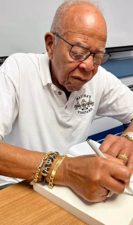 Thomas D. Williams, Wendy Williams' father, is seen signing a book in a family photo | Source: Instagram/alexcfinnie