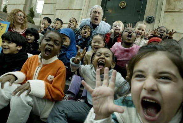 Robert Munsch and some kids make funny faces during story telling. | Photo: Getty Images