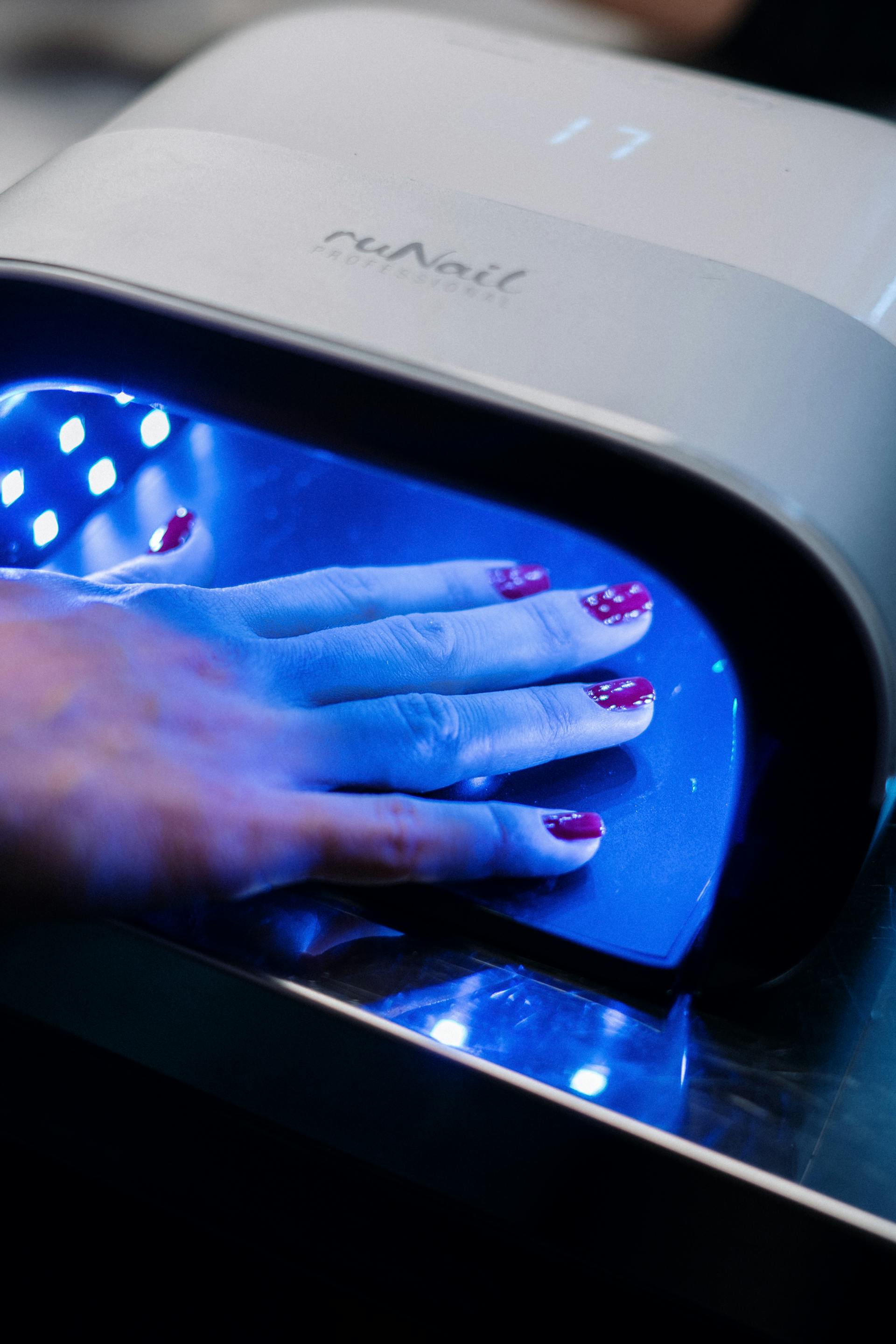 A hand in a UV nail machine | Source: Pexels