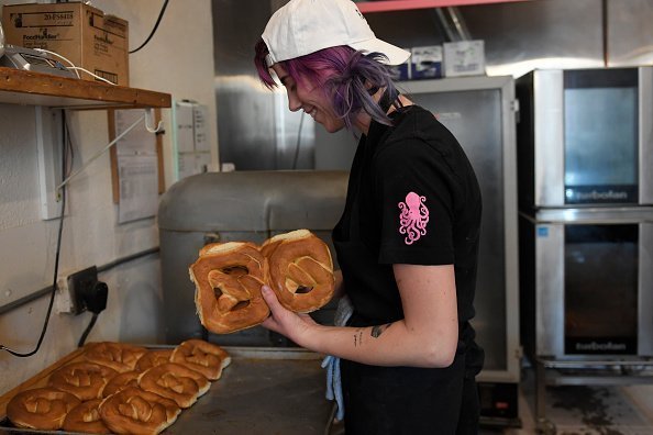  Bread baker Hope Lamb breaking apart traditional vegan pretzel buns at the Make Believe Bakery | Photo: Getty Images