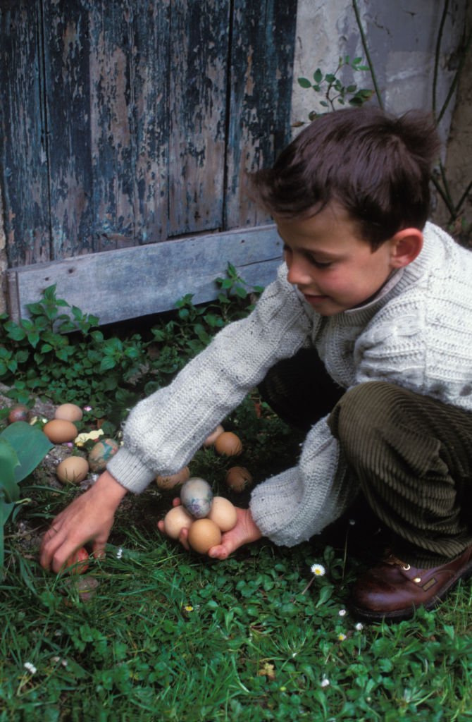 Un petit garçon en train de ramasser des oeufs de Pâques. | Photo : Getty Images
