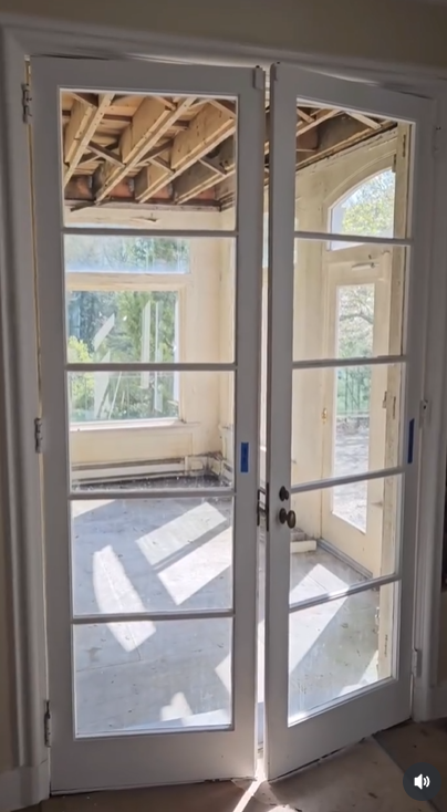 A bright, window-lined sunroom sits just off the main living area, showing signs of interior deconstruction | Source: Instagram/hudsonvalleyhouseparts